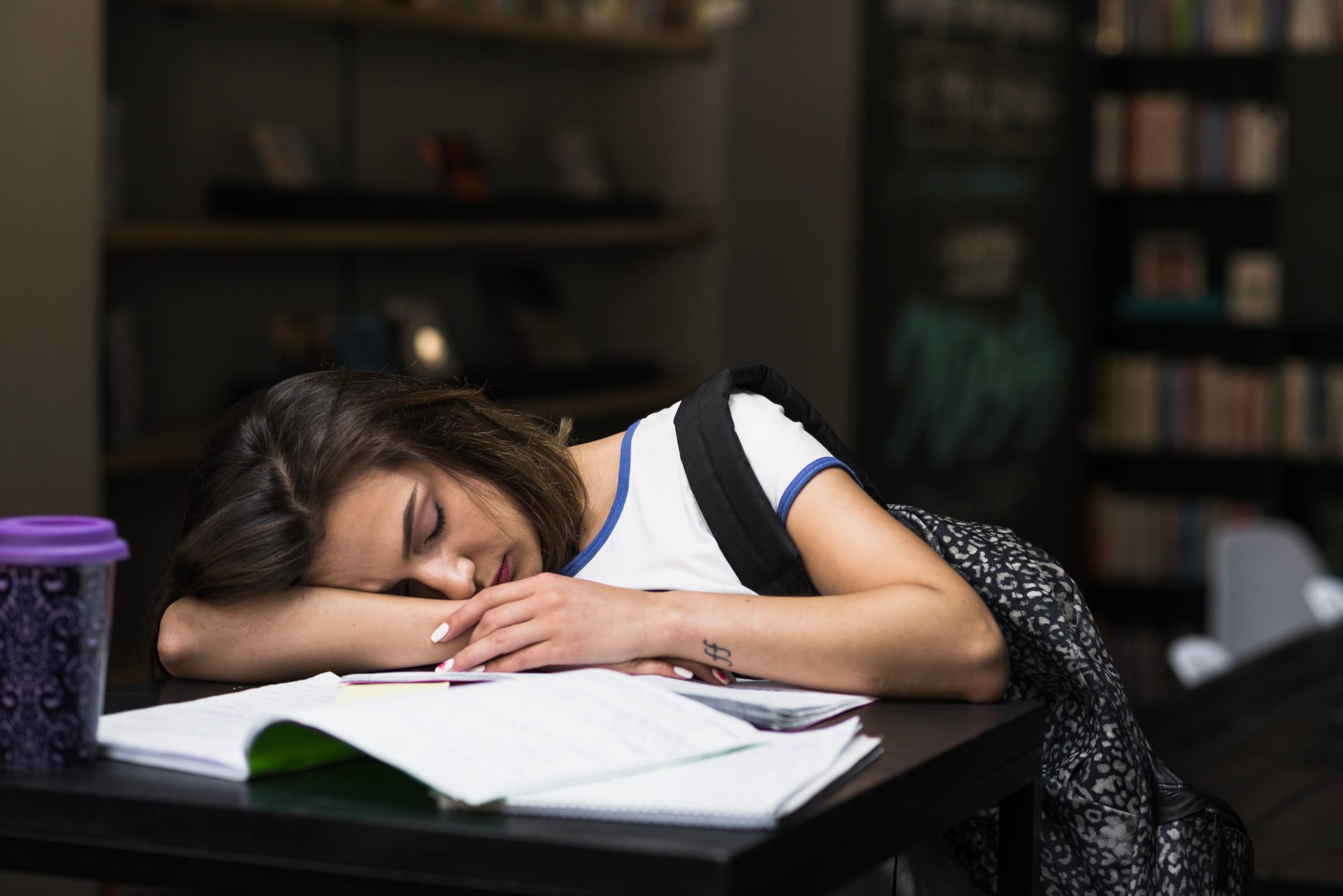 Una chica se queda dormida estudiando en la biblioteca (Magnific)
