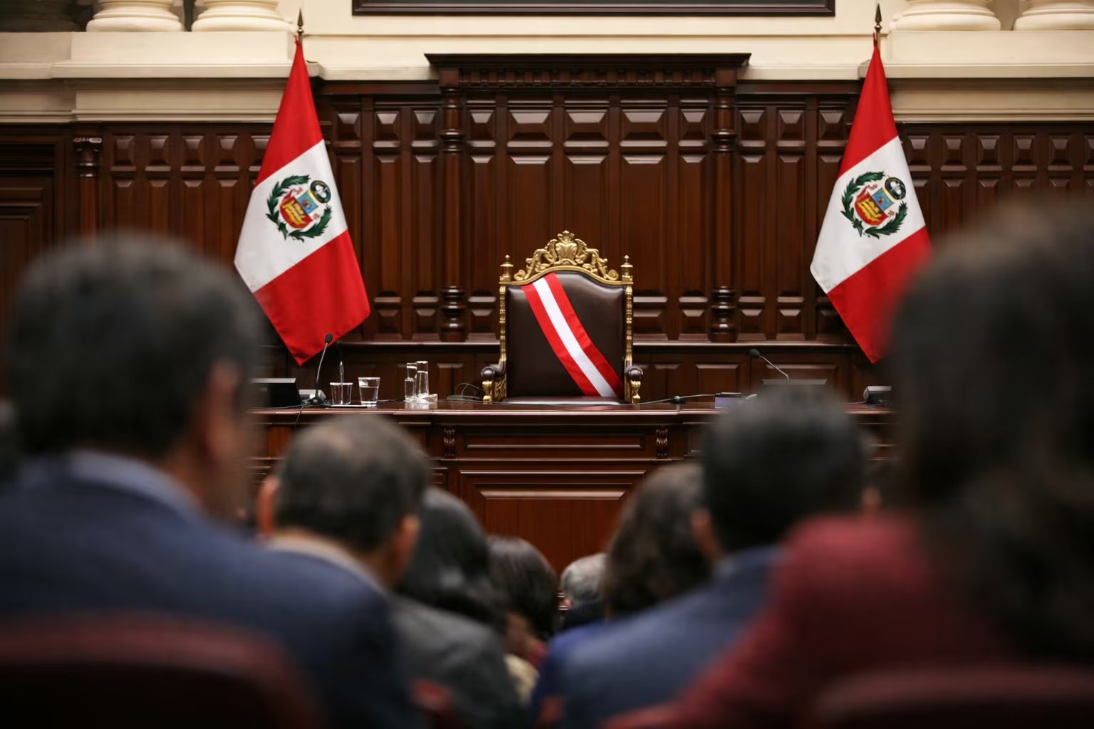 El estrado principal del Congreso de Perú, con la silla presidencial vacía y dos banderas nacionales, se observa desde la sala de sesiones. (Imagen Ilustrativa Infobae)