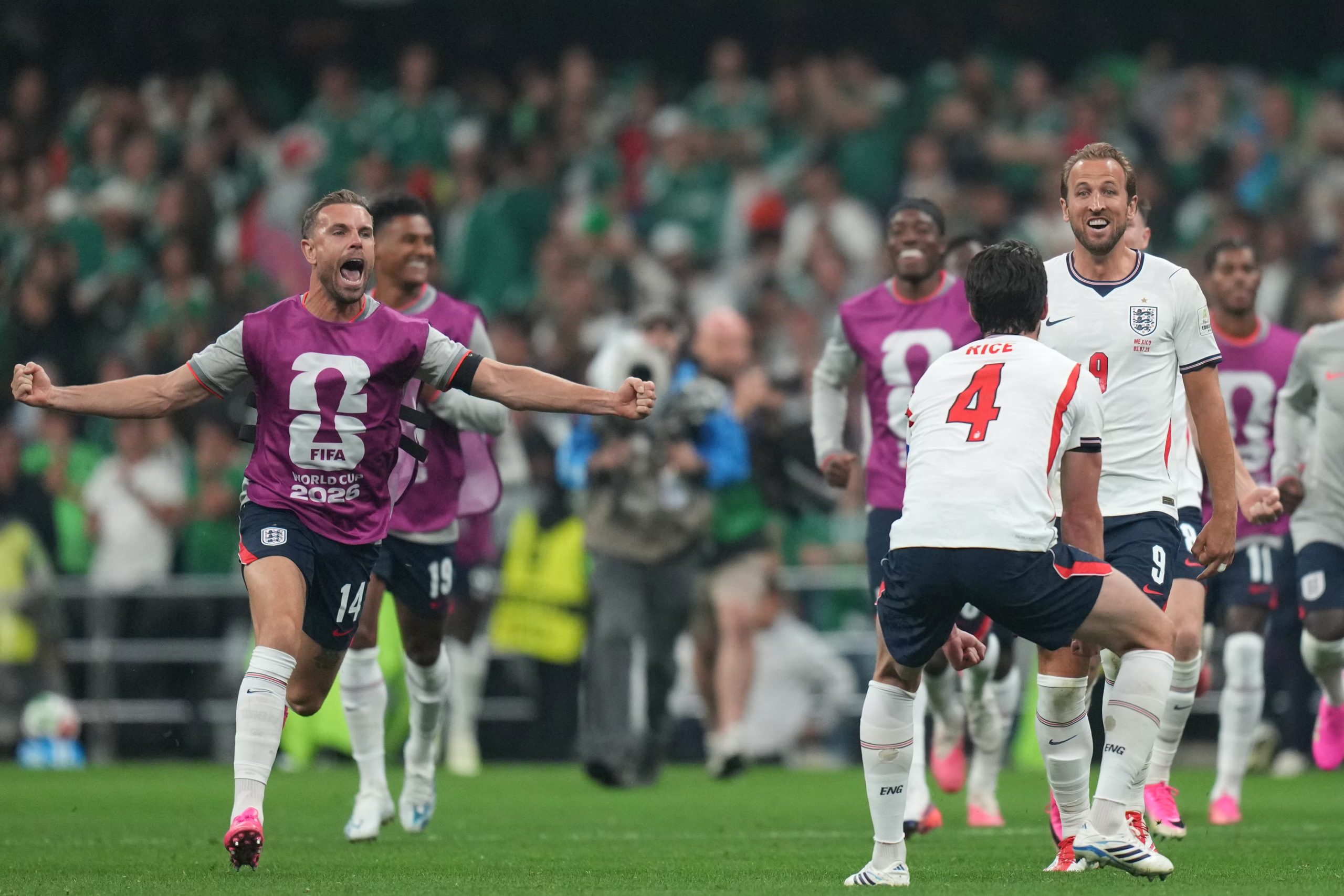 Jordan Henderson festeja con los brazos abiertos en el campo de juego, mientras sus compañeros Harry Kane y Declan Rice lo acompañan durante un partido de fútbol con la selección de Inglaterra.