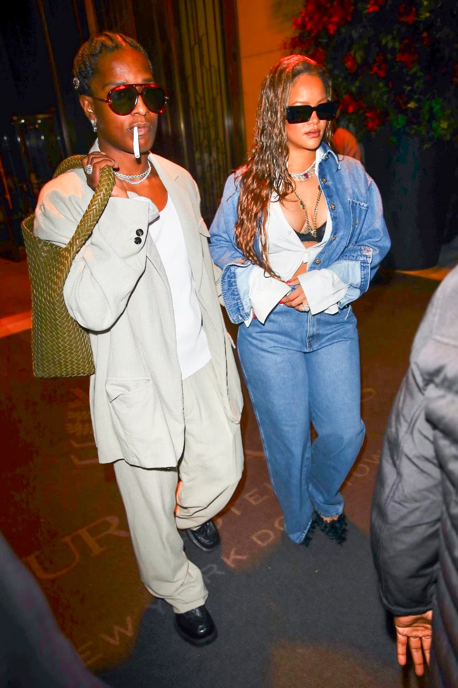 Rihanna se va al denim claro con camisa abierta y top negro, A$AP Rocky relaja la sastrería en arena con bolso tejido y mocasines (Backgrid/The Grosby Group)
