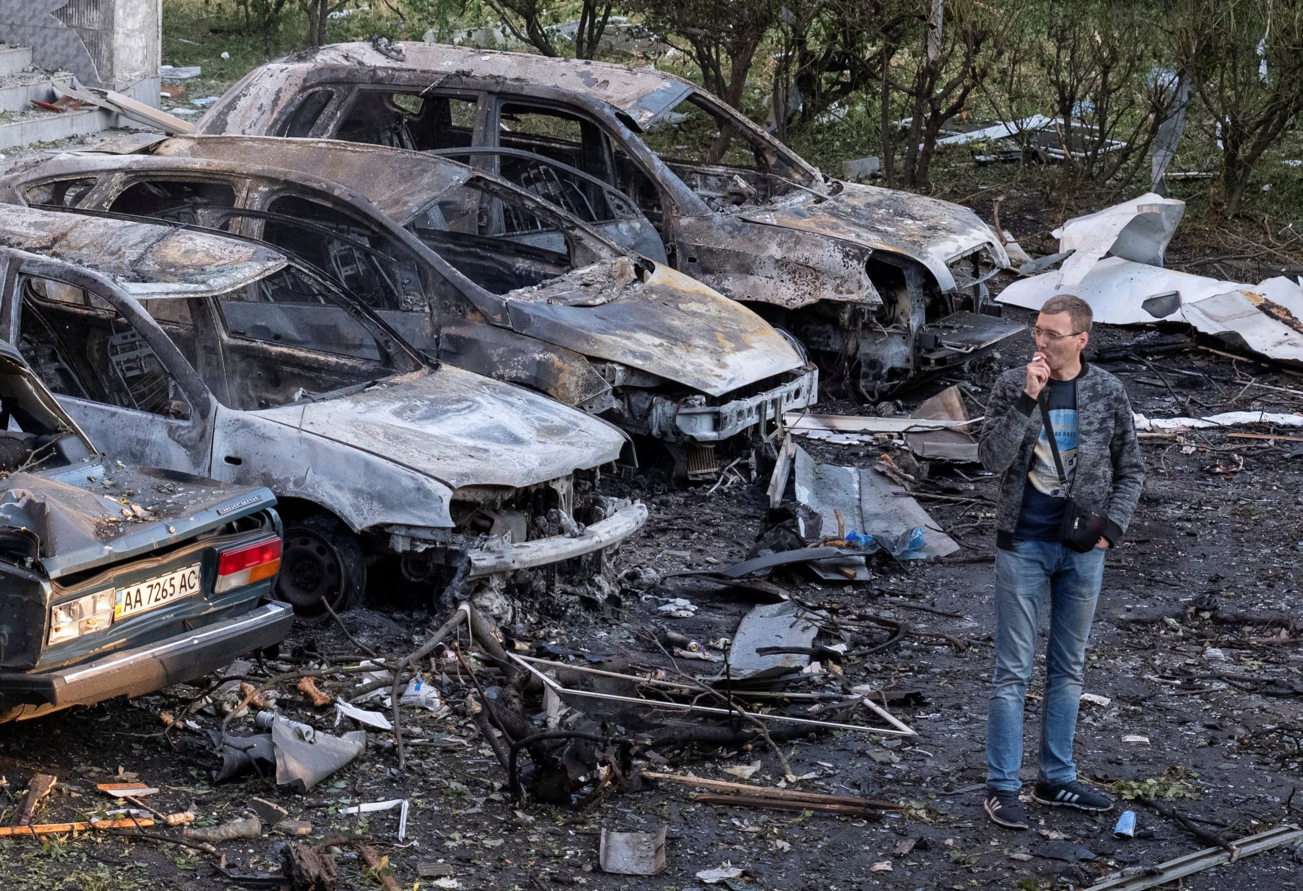Un residente fuma junto a autos quemados tras un ataque ruso con misiles en Kiev, que dejó una persona muerta y 13 heridas (REUTERS/Stringer)