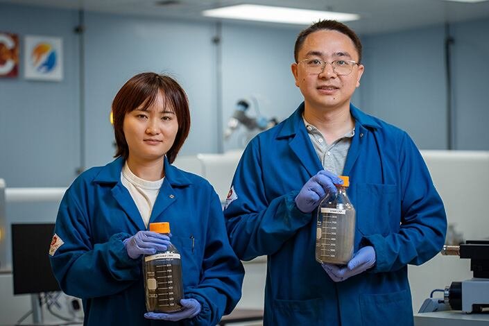 Los investigadores postdoctorales Jiao Lin y Wei Li sostienen frascos que contienen polvos del producto reciclado (LMFP) y LFP usado, respectivamente - Crédito: David Baillot/Escuela de Ingeniería Jacobs de la UC San Diego.