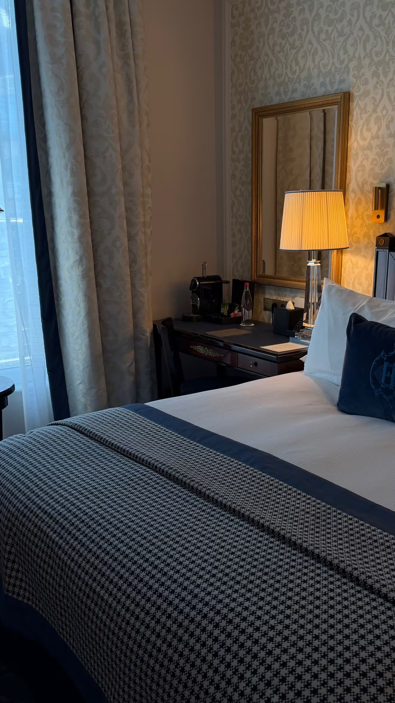 Una habitación de hotel en París, parte del viaje de vacaciones de Wanda Nara, presenta una cama con textiles decorativos y un escritorio.