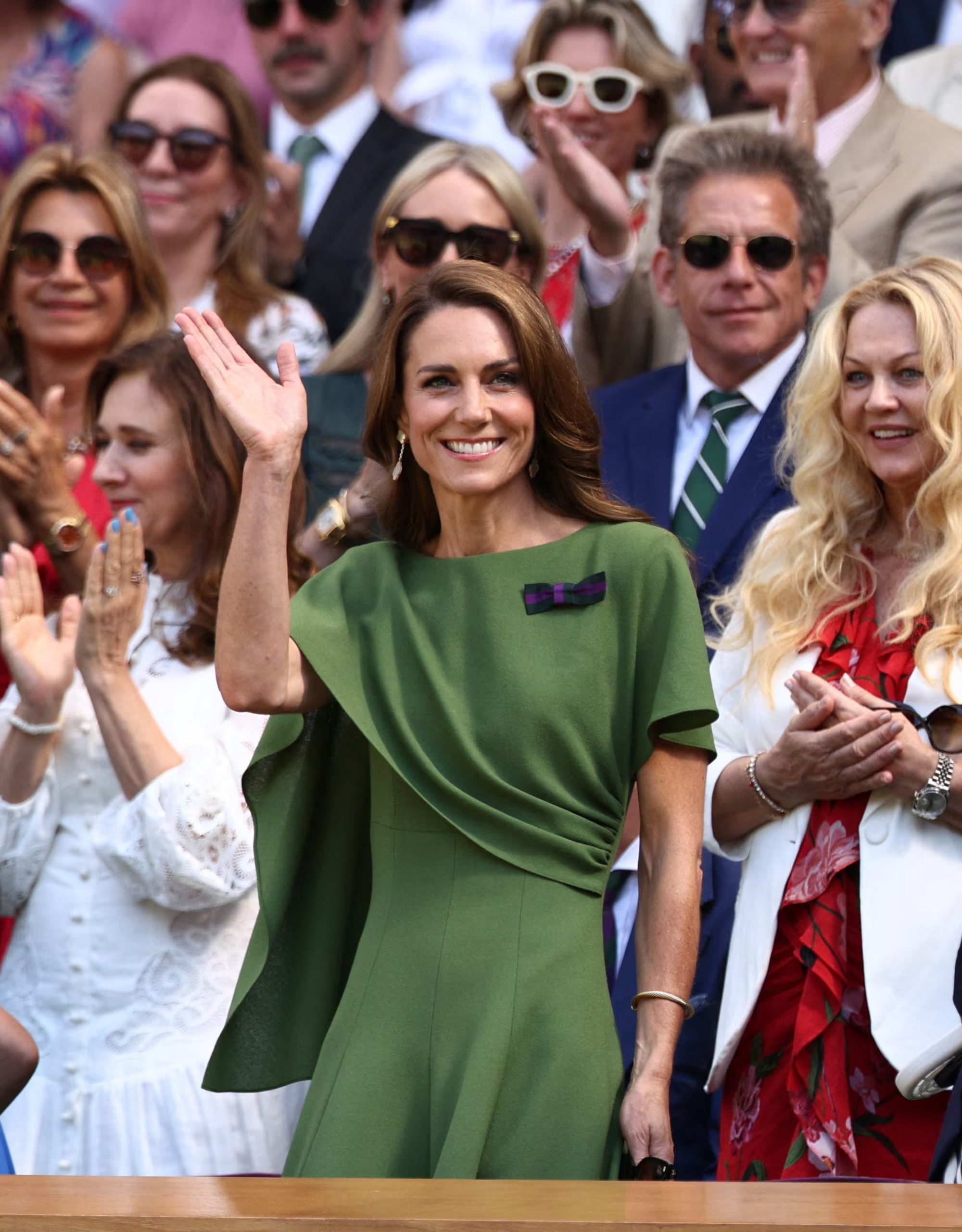 Kate Middleton luce un vestido verde con drapeados y broche púrpura y verde, con joyería discreta y ondas suaves