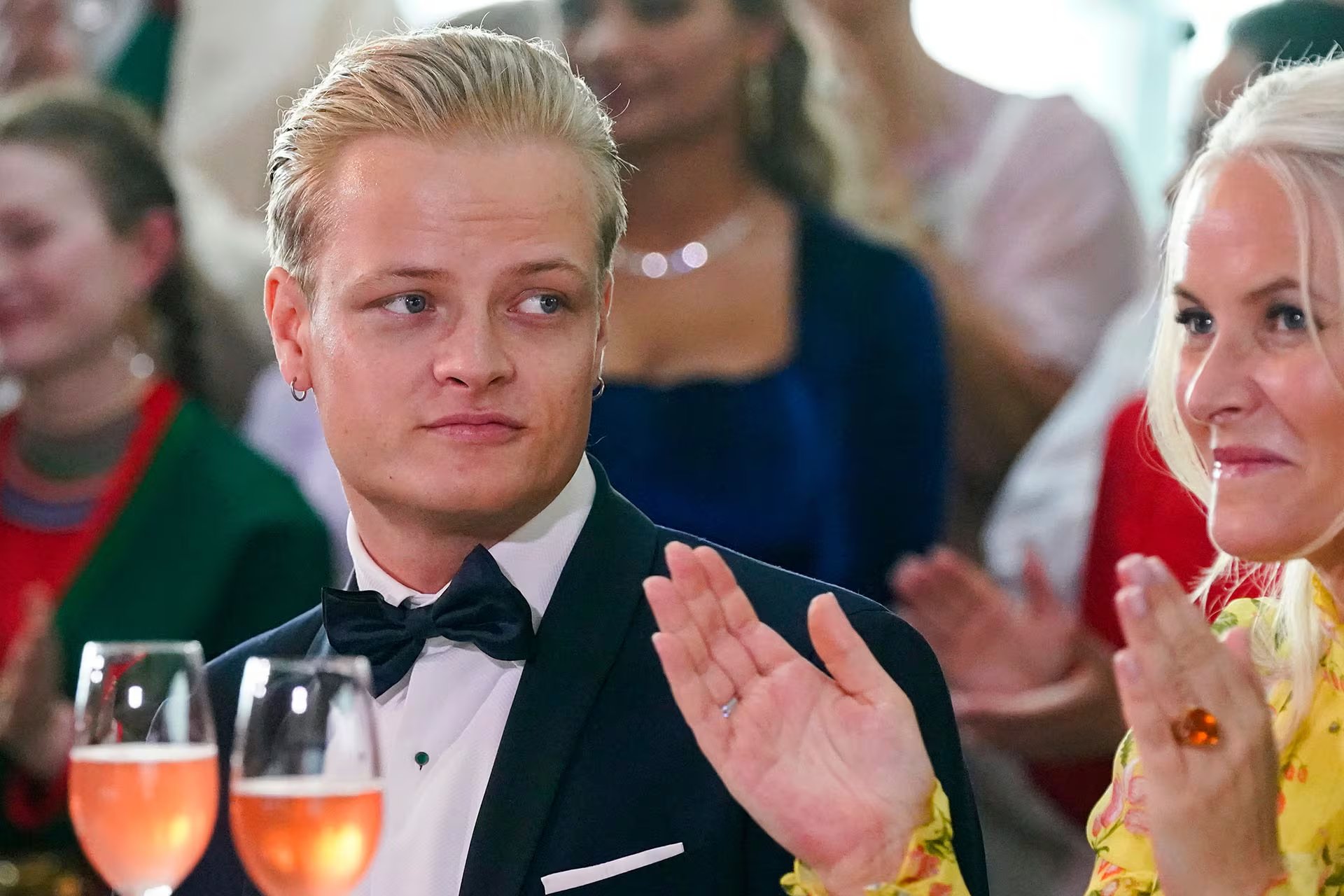 Marius Borg Høiby y la Princesa Heredera Mette-Marit de Noruega comparten un momento durante una recepción, aplaudiendo entre otros asistentes en un ambiente festivo (AP)