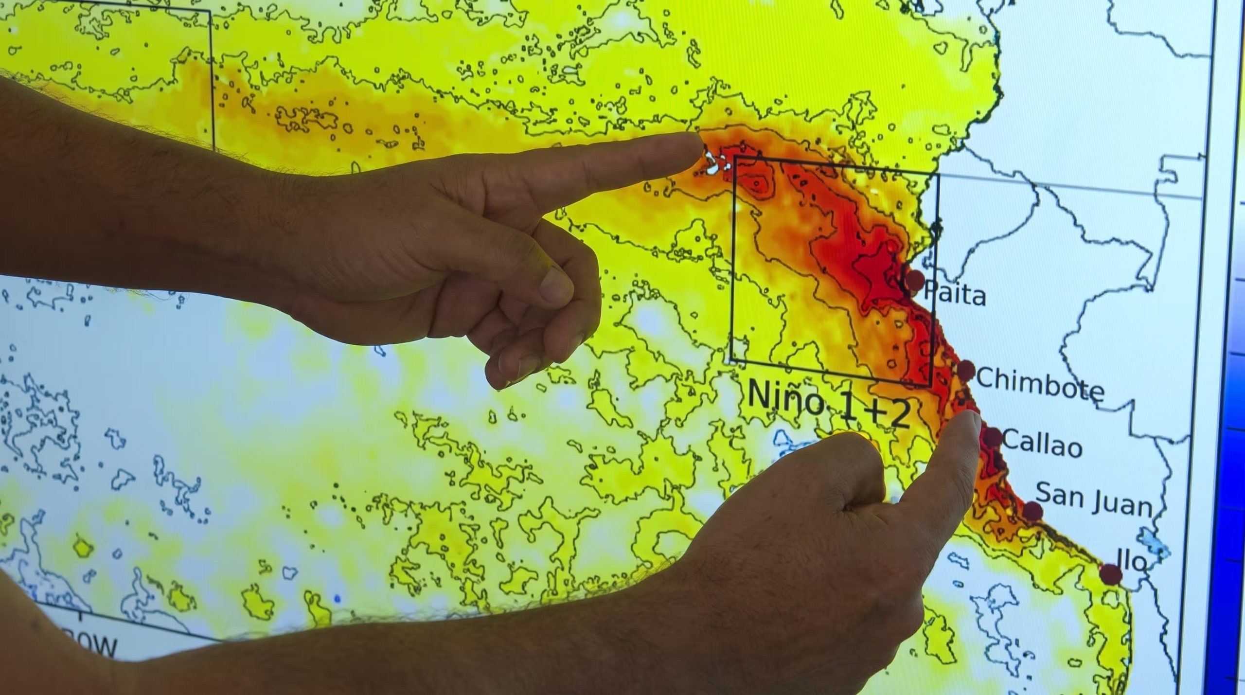 Dos manos señalan un mapa que indica las anomalías de temperatura de la superficie del mar frente a la costa de Perú, asociadas al fenómeno El Niño. (Senamhi)