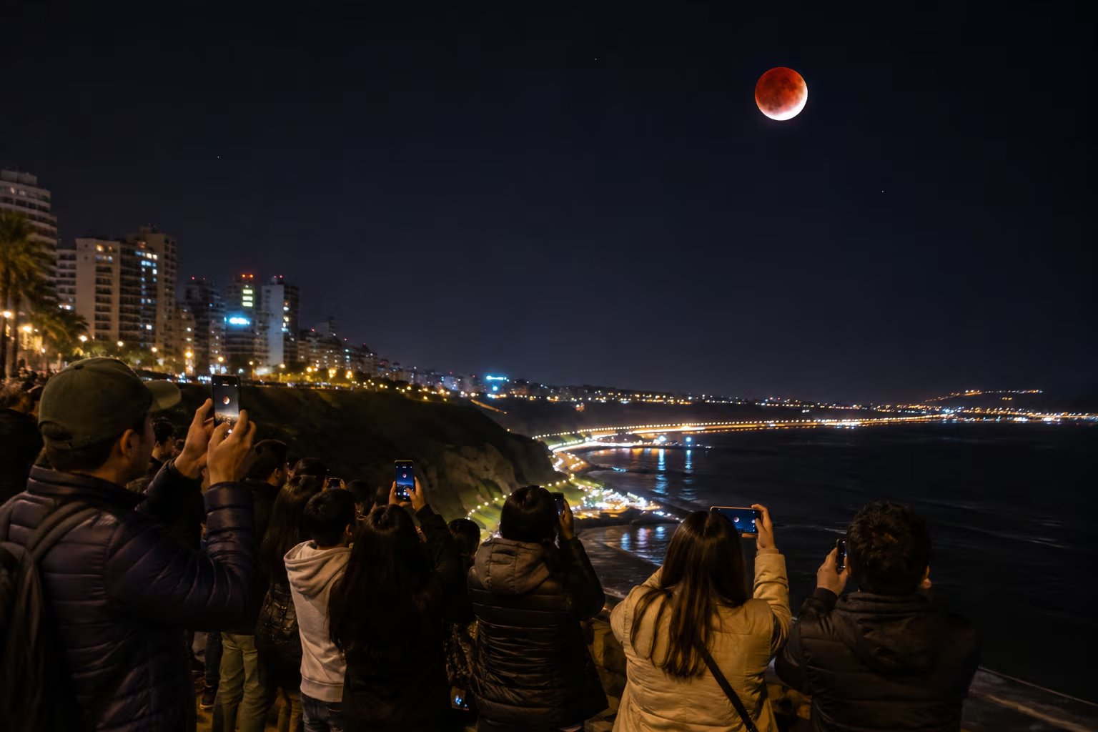 Varias personas fotografían un eclipse lunar con sus teléfonos móviles desde la costa de Lima el 27 de agosto. (VisualesIA)