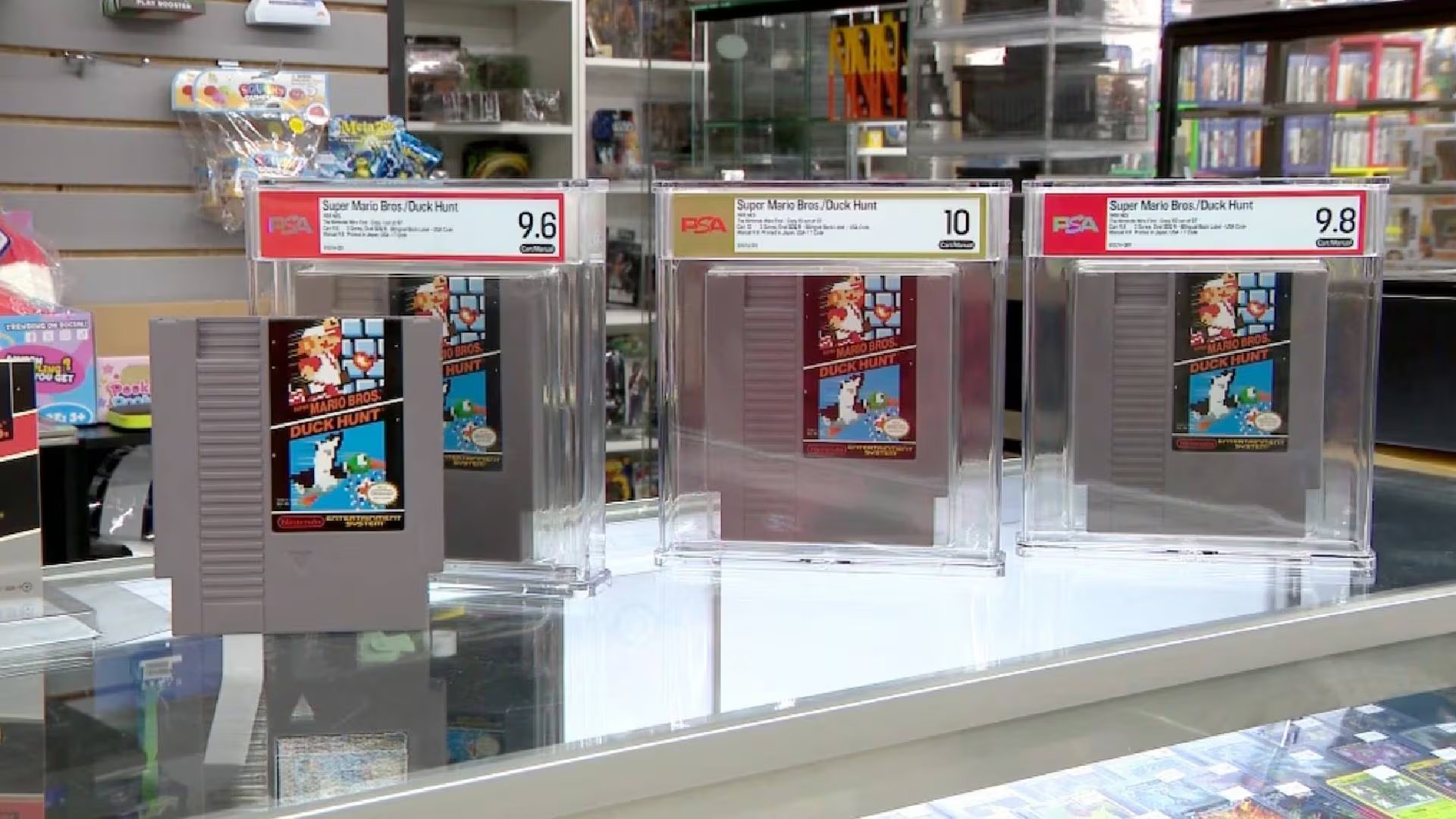 Cuatro cartuchos del videojuego Super Mario Bros. / Duck Hunt de Nintendo, incluyendo tres ejemplares certificados por PSA con calificaciones de 9.6, 10 y 9.8, se exhiben en un establecimiento (ABC )