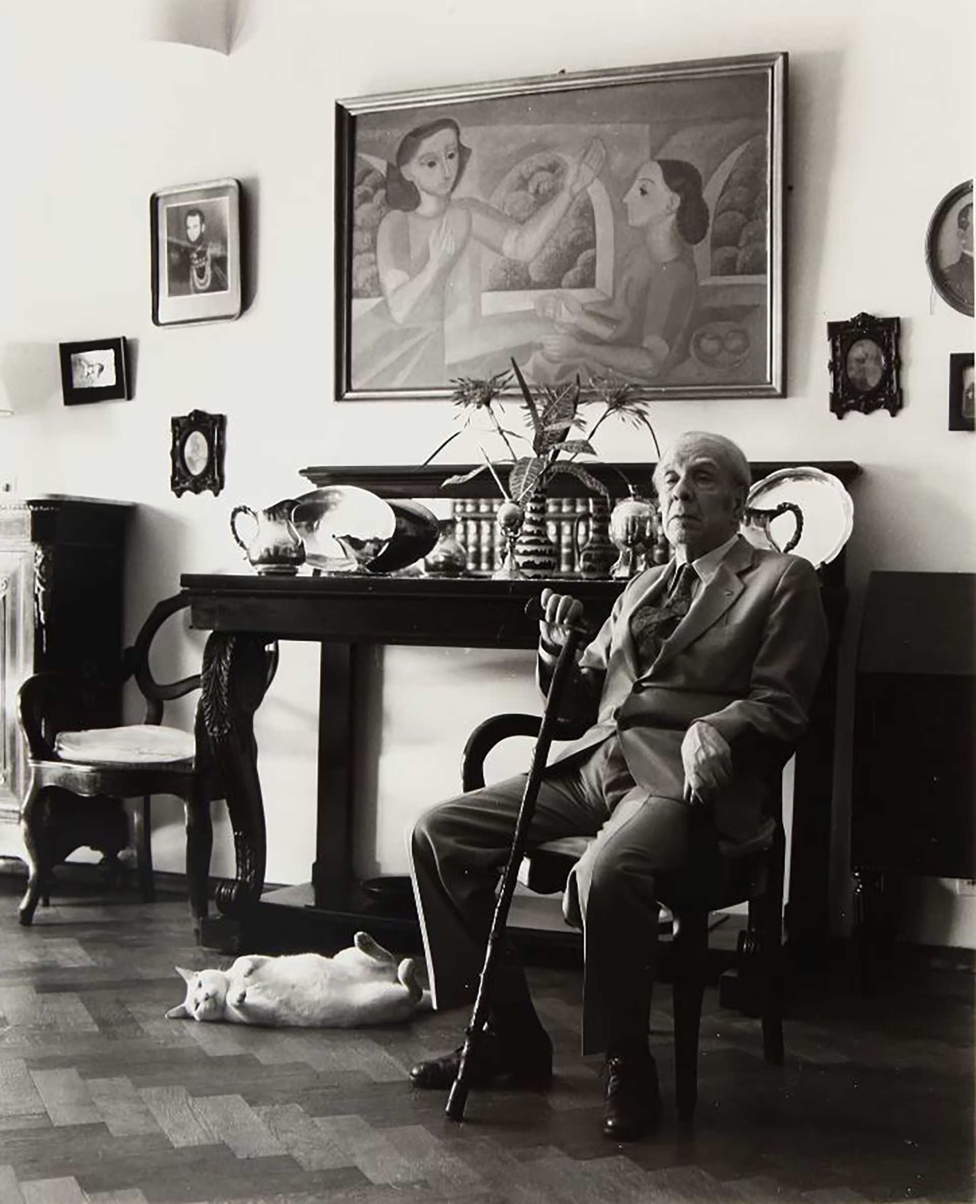 El icónico escritor argentino Jorge Luis Borges posa pensativo en su hogar, acompañado por su gato y un ambiente lleno de arte, en una fotografía de Julie Méndez Ezcurra