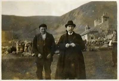 El misionero Dugald Maclean junto a un joven de San Kilda, en abril de 1911. Al fondo, las cabañas de piedra de Village Bay, el único asentamiento permanente en la isla de Hirta