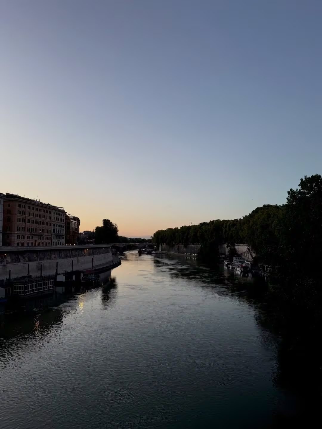 El río Tíber en Roma se ilumina con los últimos rayos del sol al caer la tarde, ofreciendo una vista tranquila y pintoresca durante un viaje memorable.