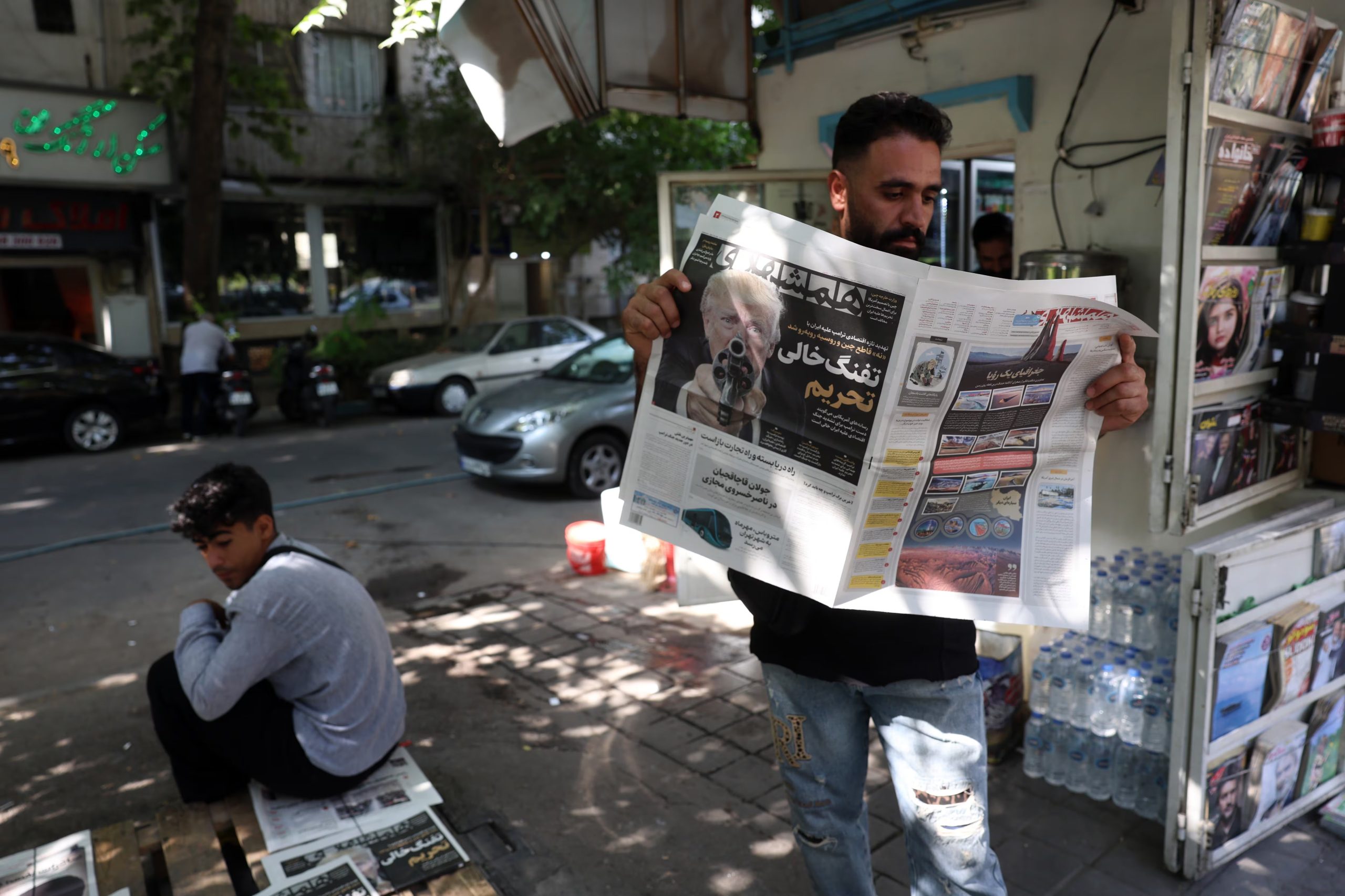 Un hombre iraní lee un ejemplar del diario iraní Hamshahri que muestra una fotografía del presidente estadounidense Donald Trump y un titular en persa que dice: