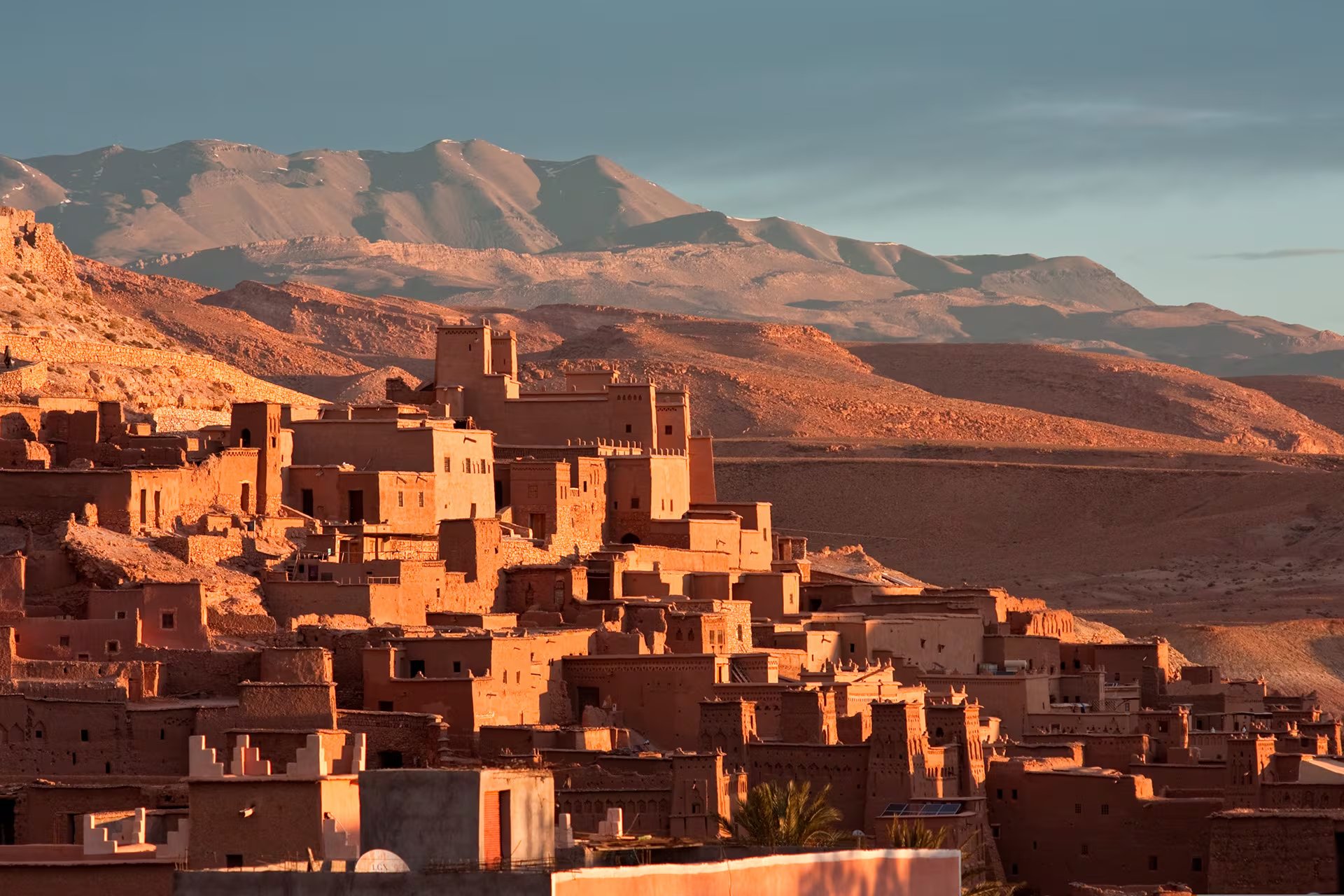 El ksar de Aït Benhaddou muestra sus edificaciones de adobe iluminadas por la luz del atardecer, con montañas áridas al fondo. (Pixabay)