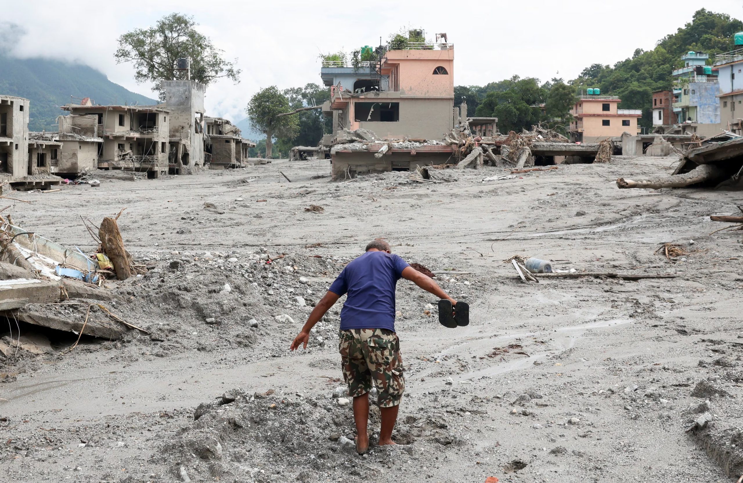 Un hombre avanza por una calle cubierta de barro junto a casas dañadas tras las inundaciones repentinas y el deslizamiento de tierra en Devighat, distrito de Nuwakot, Nepal, el 29 de agosto de 2026 (REUTERS/Adnan Abidi)