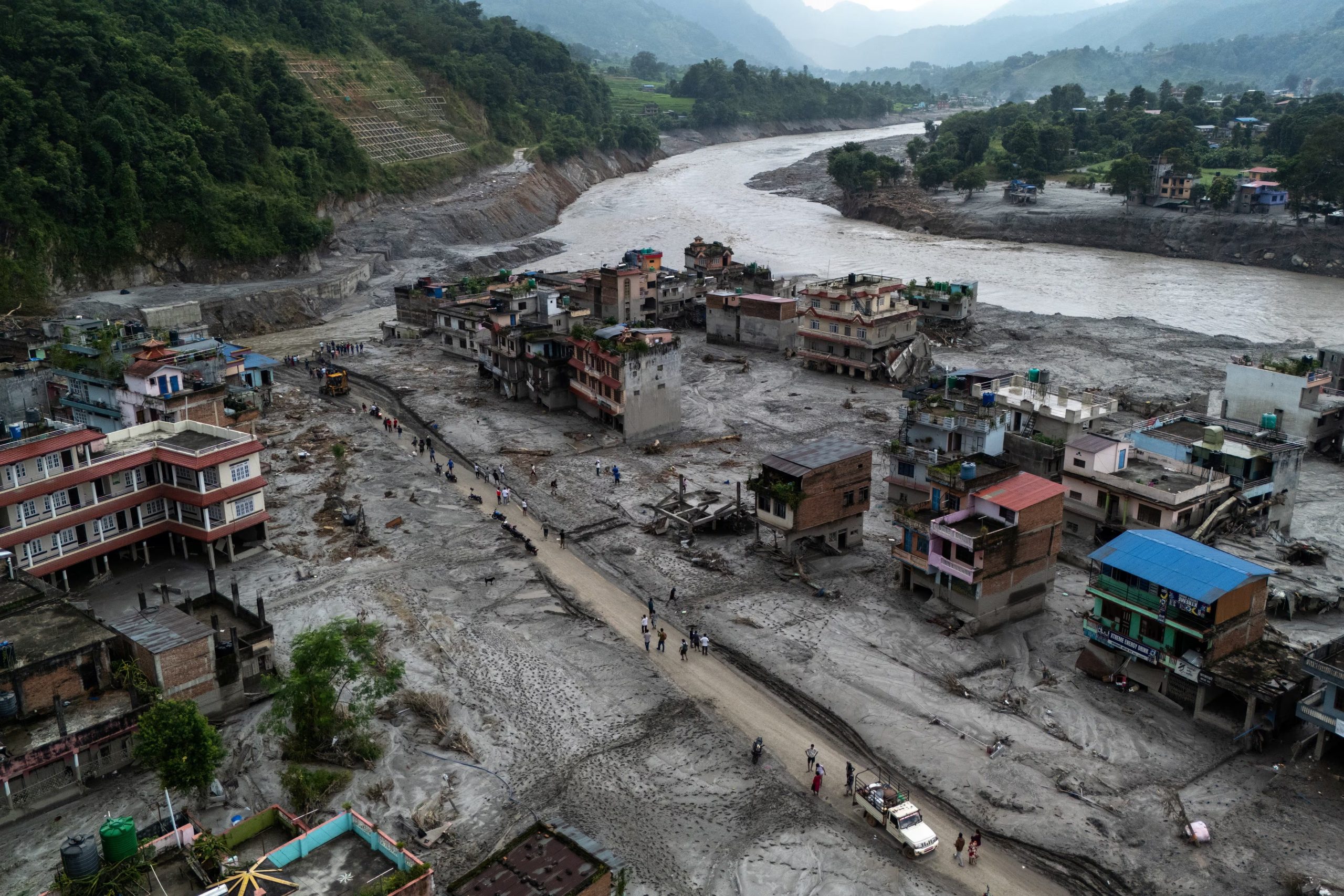 Vista desde un dron de personas caminando por una carretera y casas cubiertas de barro tras las mortales inundaciones repentinas y deslizamientos de tierra en Devighat, distrito de Nuwakot, Nepal, el 29 de agosto de 2026 (REUTERS/Athit Perawongmetha)