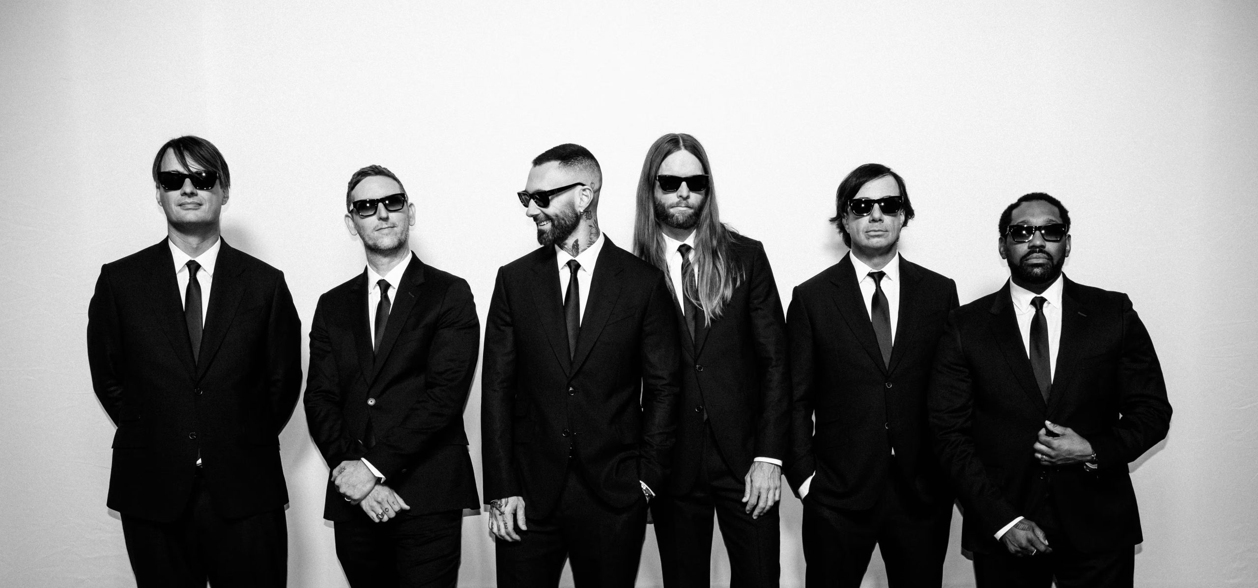 Los miembros de Maroon 5, vestidos con trajes oscuros y gafas de sol, posan en una foto en blanco y negro para la promoción de su último trabajo, 'All Night'.