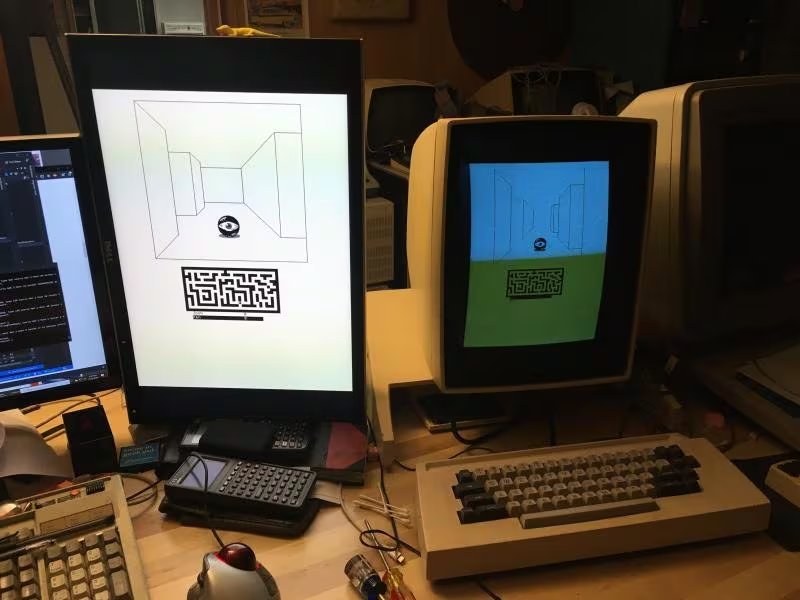 Dos monitores, uno moderno y otro perteneciente a un Xerox Alto (c. 1973), la primera computadora personal, muestran un mismo juego de laberinto en un escritorio con periféricos (Crédito: Josh Dersch)