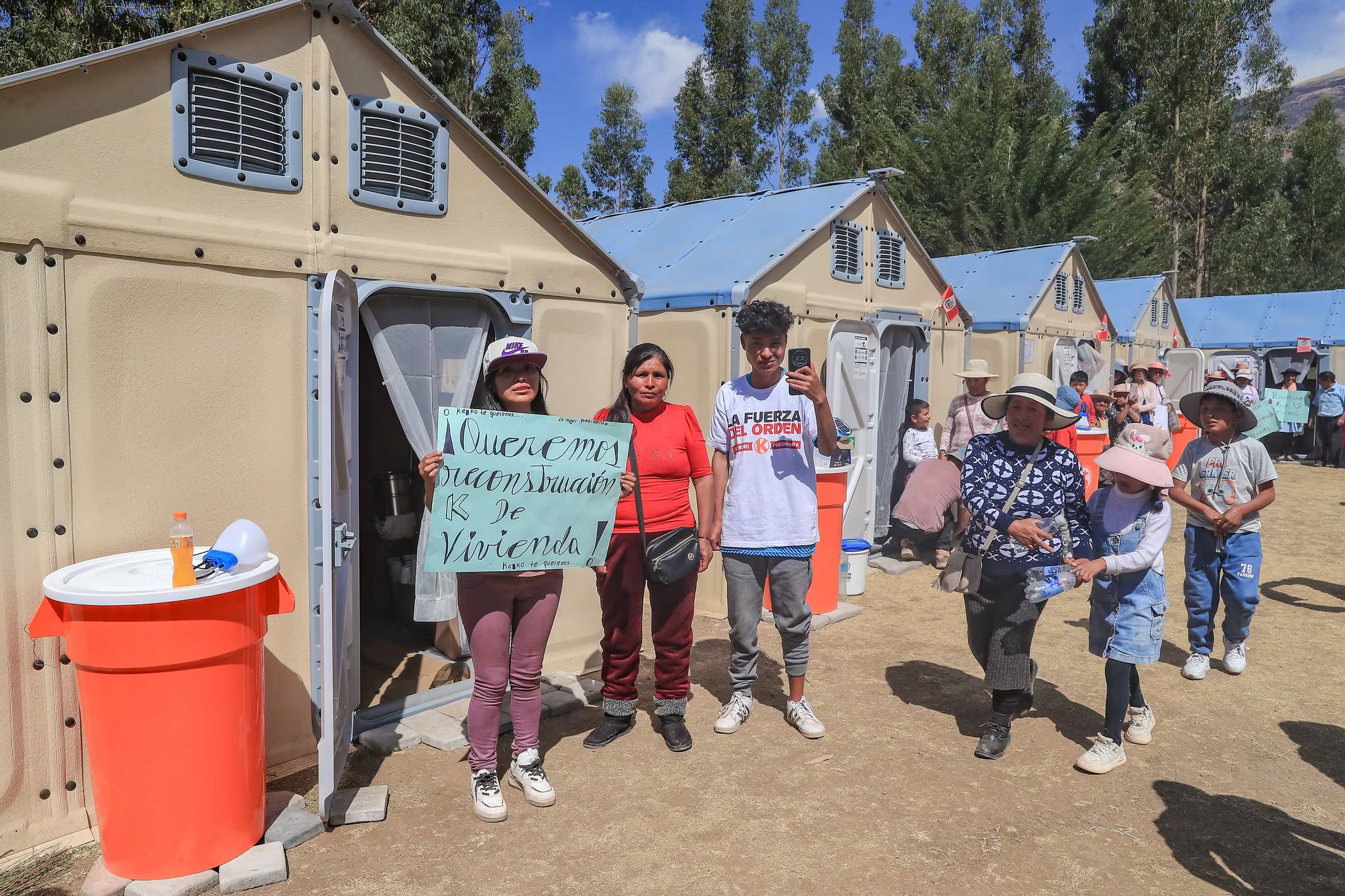 Un grupo de damnificados por el sismo en Junín sostiene un cartel para exigir la reconstrucción de sus casas ante módulos de vivienda temporal. (Flickr / Presidencia del Perú)
