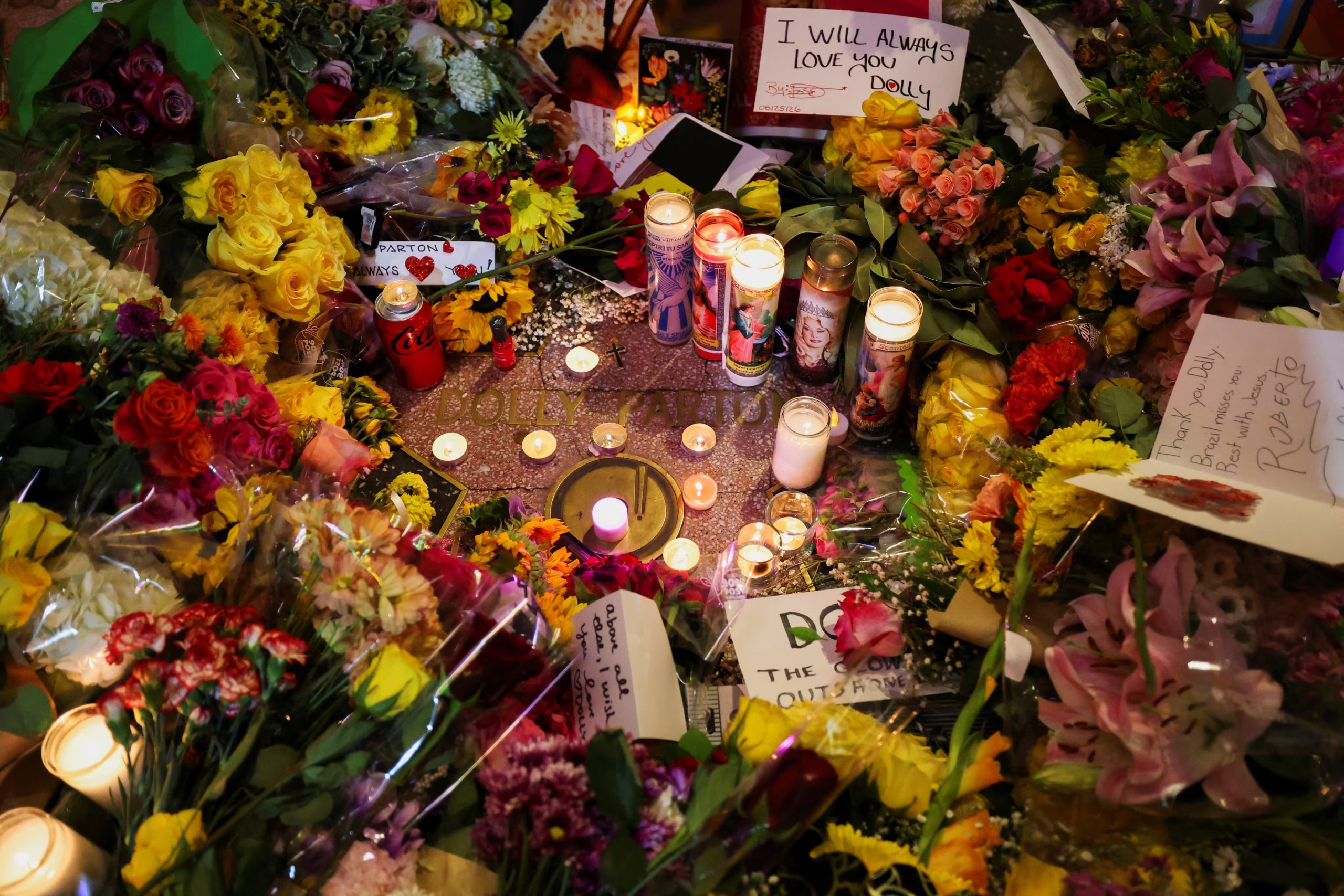 Carteles, velas y flores cerca de la estrella de Dolly Parton en el Paseo de la Fama de Hollywood tras el anuncio de su fallecimiento a los 80 años, en Los Ángeles, California, EE. UU., el 25 de agosto de 2026. (REUTERS/Mario Anzuoni)