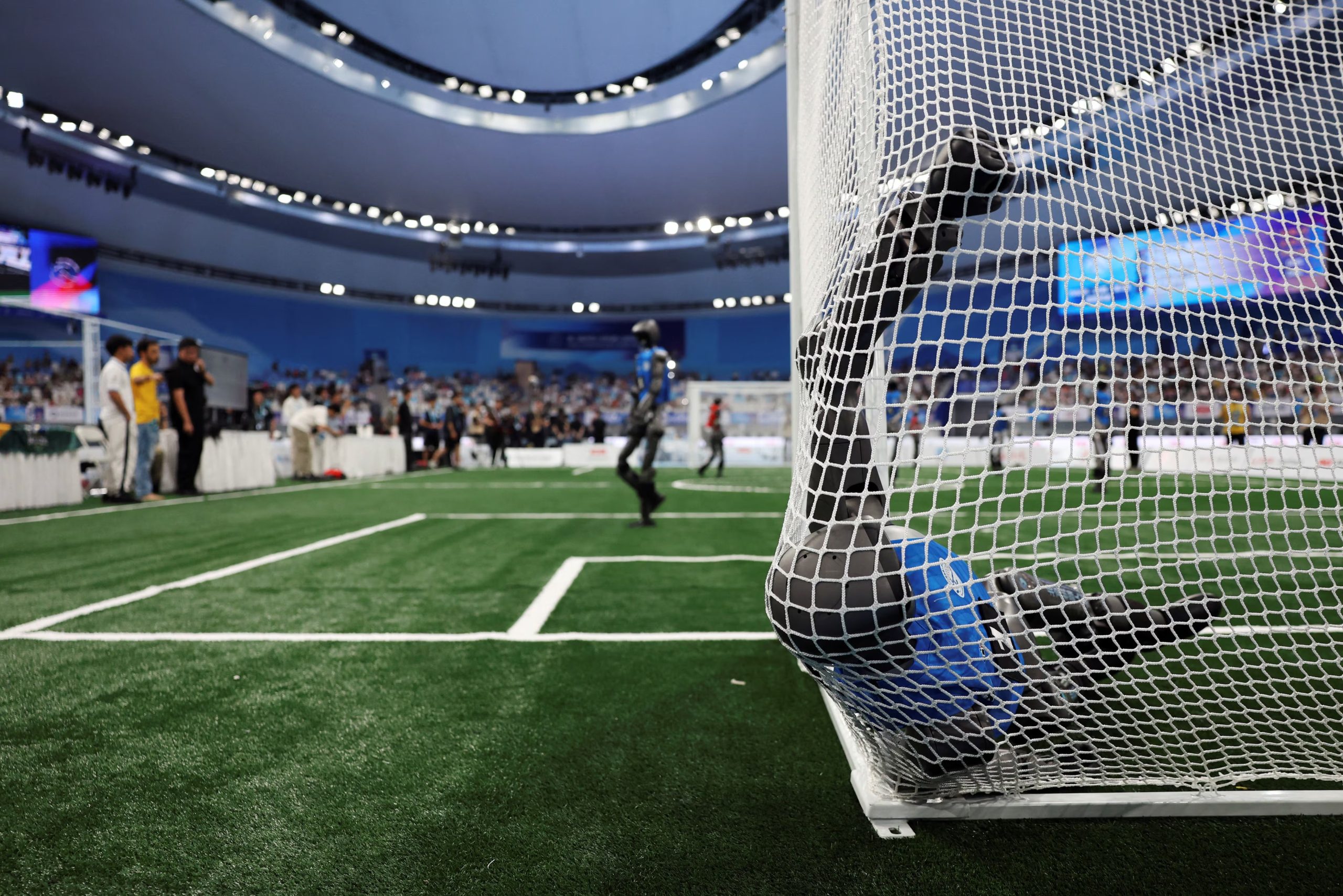 Un robot humanoide jugador de fútbol cae dentro de una portería durante un partido de cuartos de final (REUTERS/Florence Lo)

