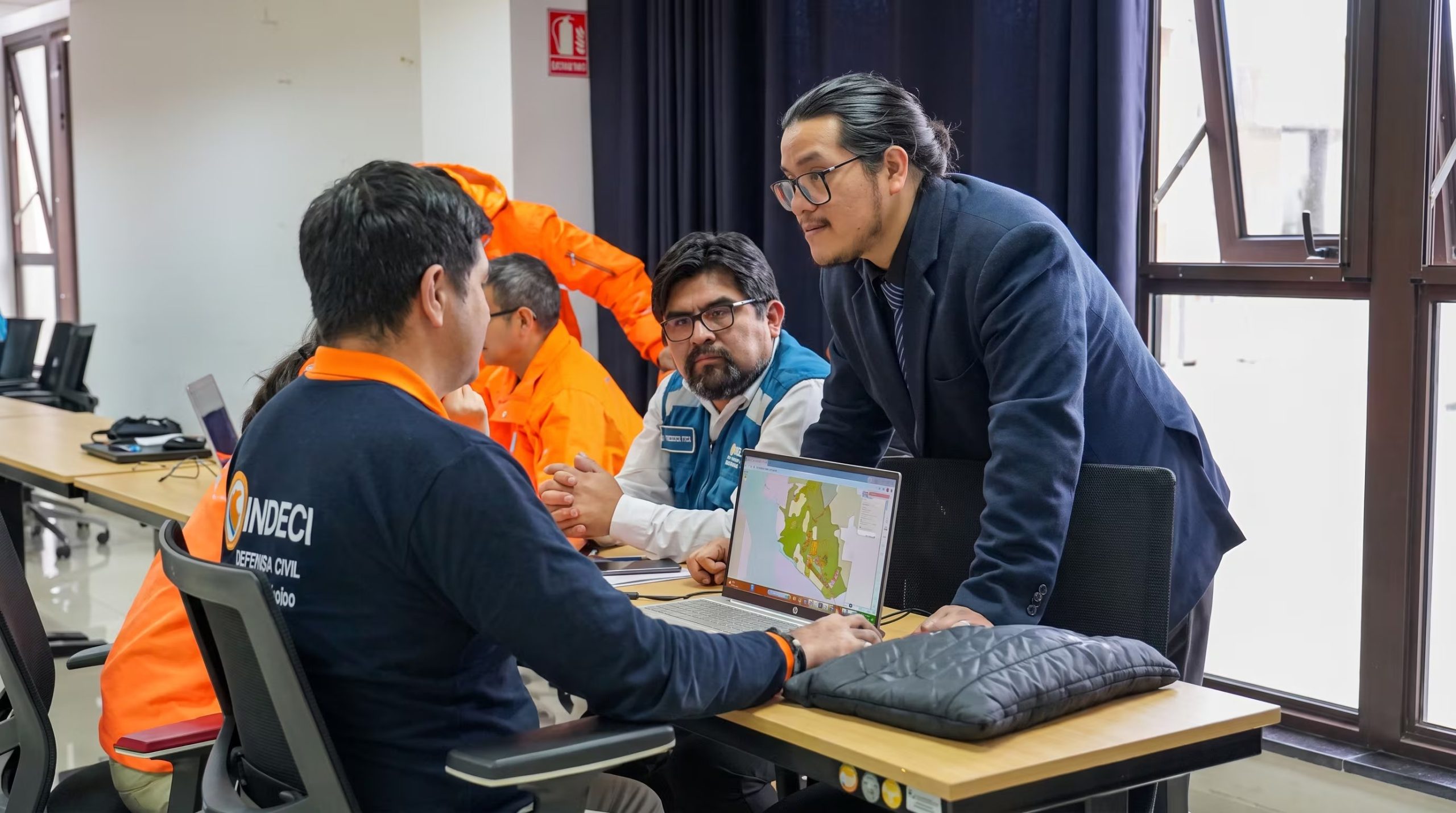 Especialistas de Indeci revisan información cartográfica en una computadora portátil durante un ejercicio de aplicación del sistema SEIDAS en Perú. (Agencia Andina/UNI)