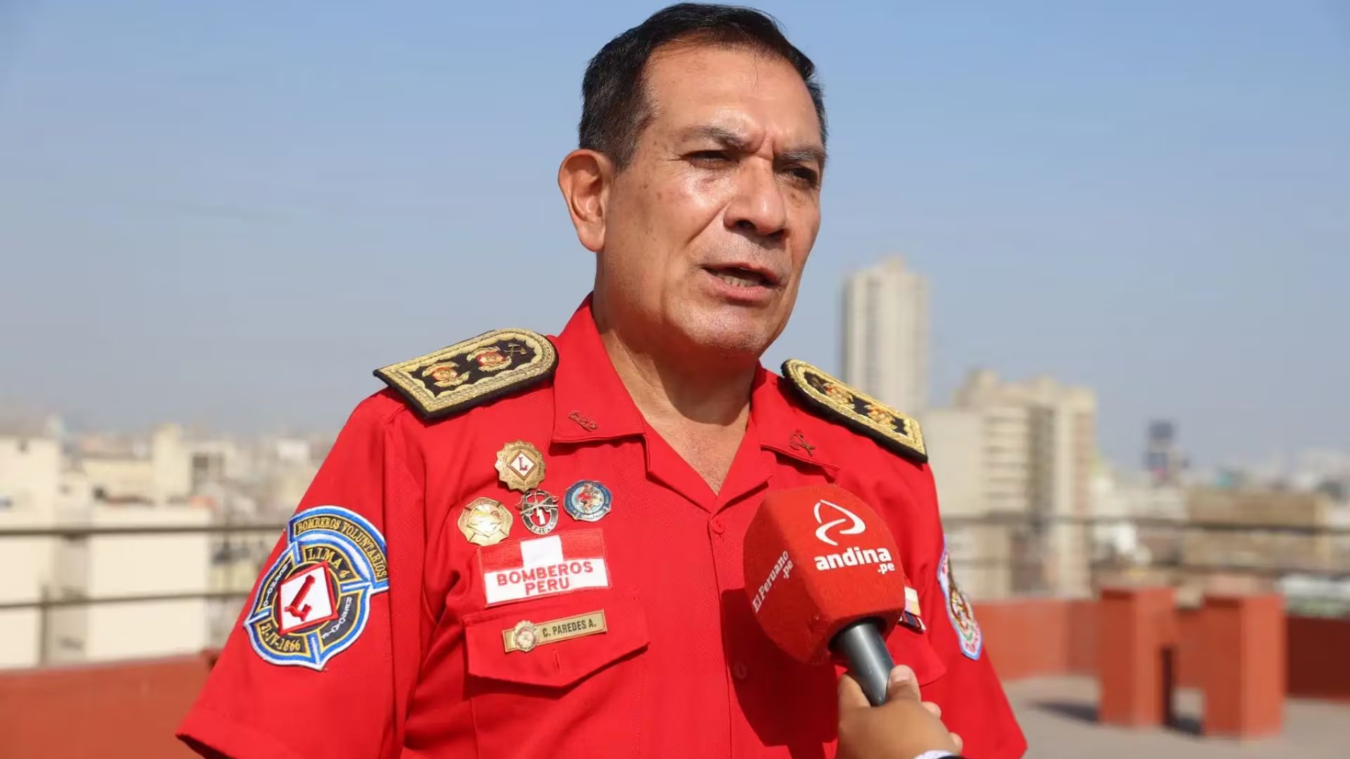 El comandante Carlos Paredes, del Cuerpo de Bomberos del Perú, ofrece declaraciones sobre prevención sísmica a un medio de comunicación en una azotea. (Agencia Andina)