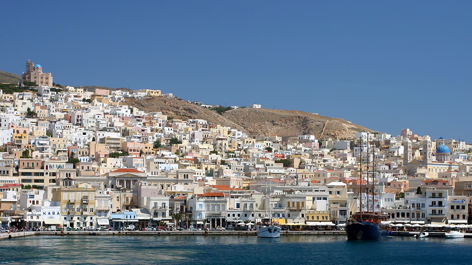 Syros, capital de las Cícladas, combina arquitectura neoclásica, playas y una gran población de gatos callejeros en un entorno de vida local (Wikipedia)