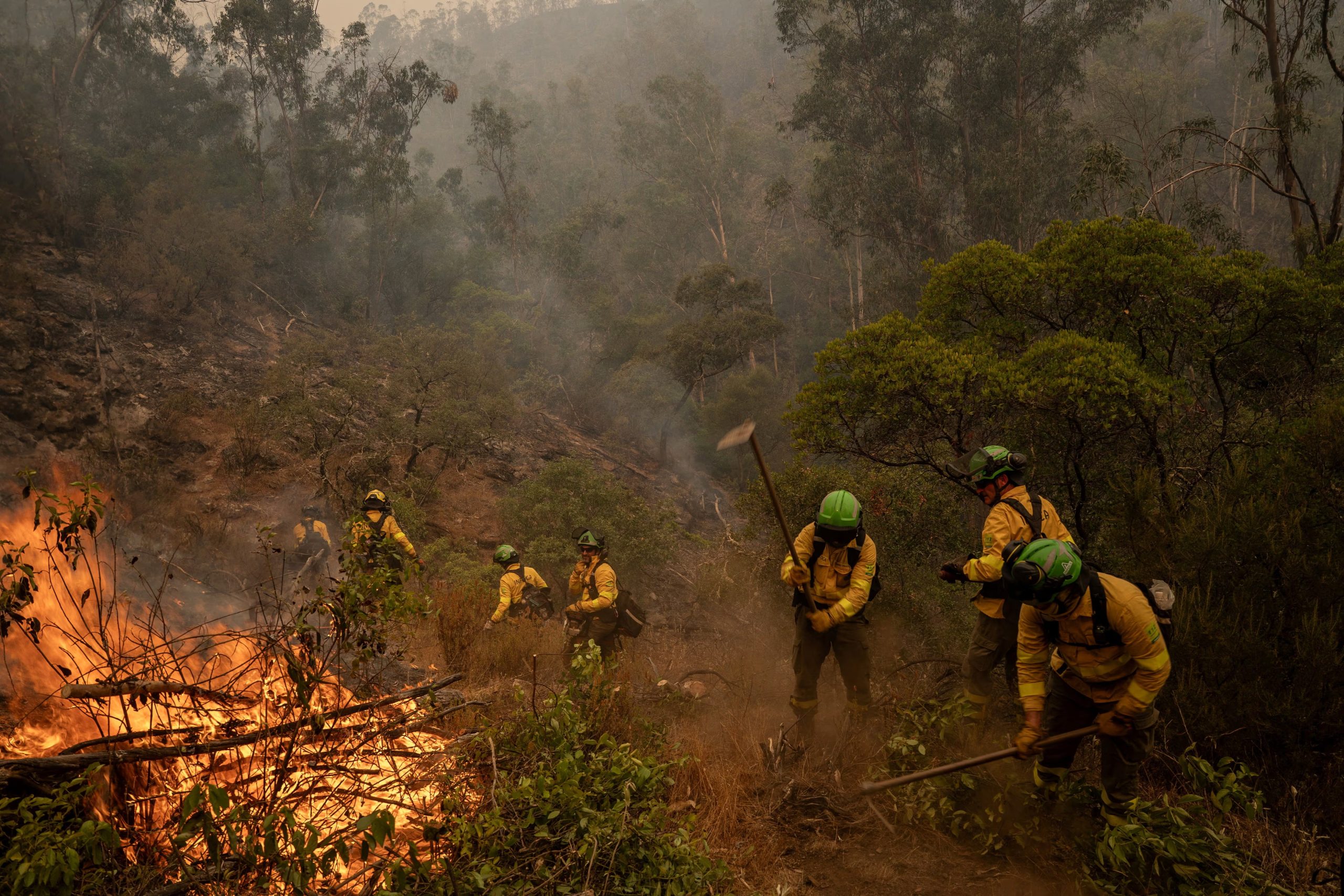 Miembros de las unidades 401 y 402 de BRICA en Granada utilizan herramientas manuales para contener un incendio forestal en Niebla, Huelva (España), el 8 de agosto de 2026. REUTERS/Mikel Konate
