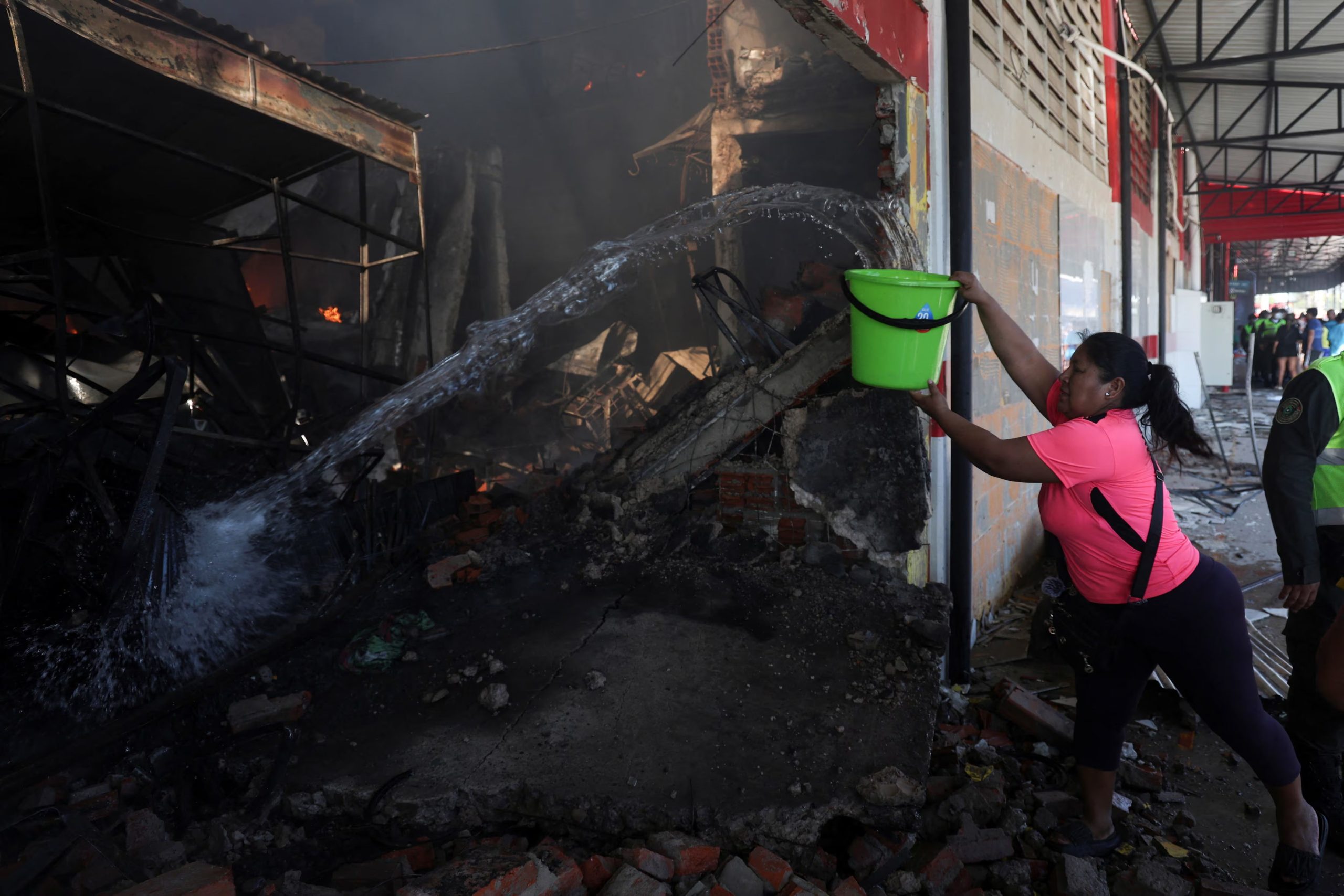 Una mujer echa un balde de agua a un puesto incendiado en el mercado de Barrio Lindo, en Santa Cruz, Bolivia. 6 de agosto de 2026. REUTERS/Ipa Ibanez