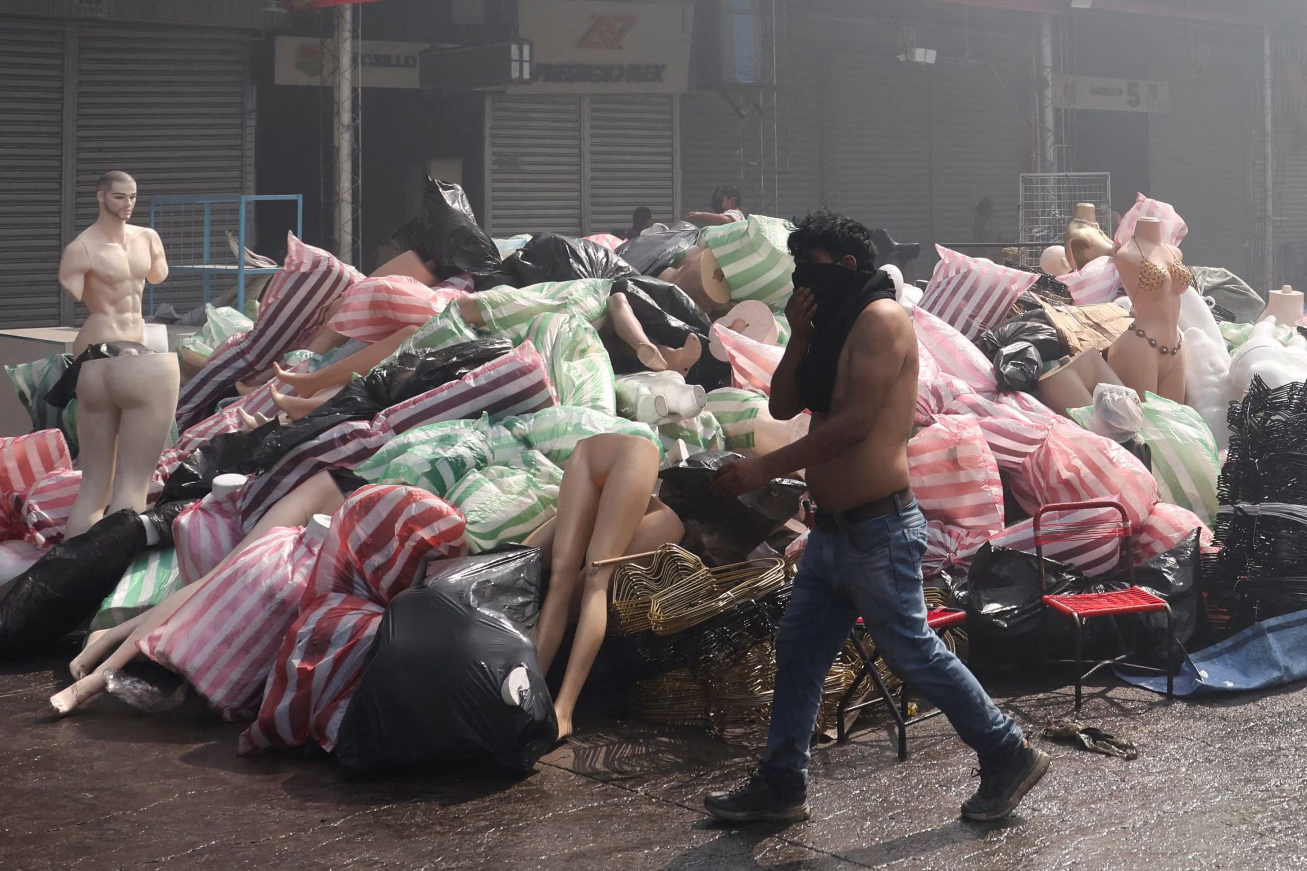 Un hombre se cubre el rostro y pasa delante de mercadería rescatada del incendio en la Feria de Barrio Lindo, en Santa Cruz, Bolivia. 6 de agosto de 2026. REUTERS/Ipa Ibanez