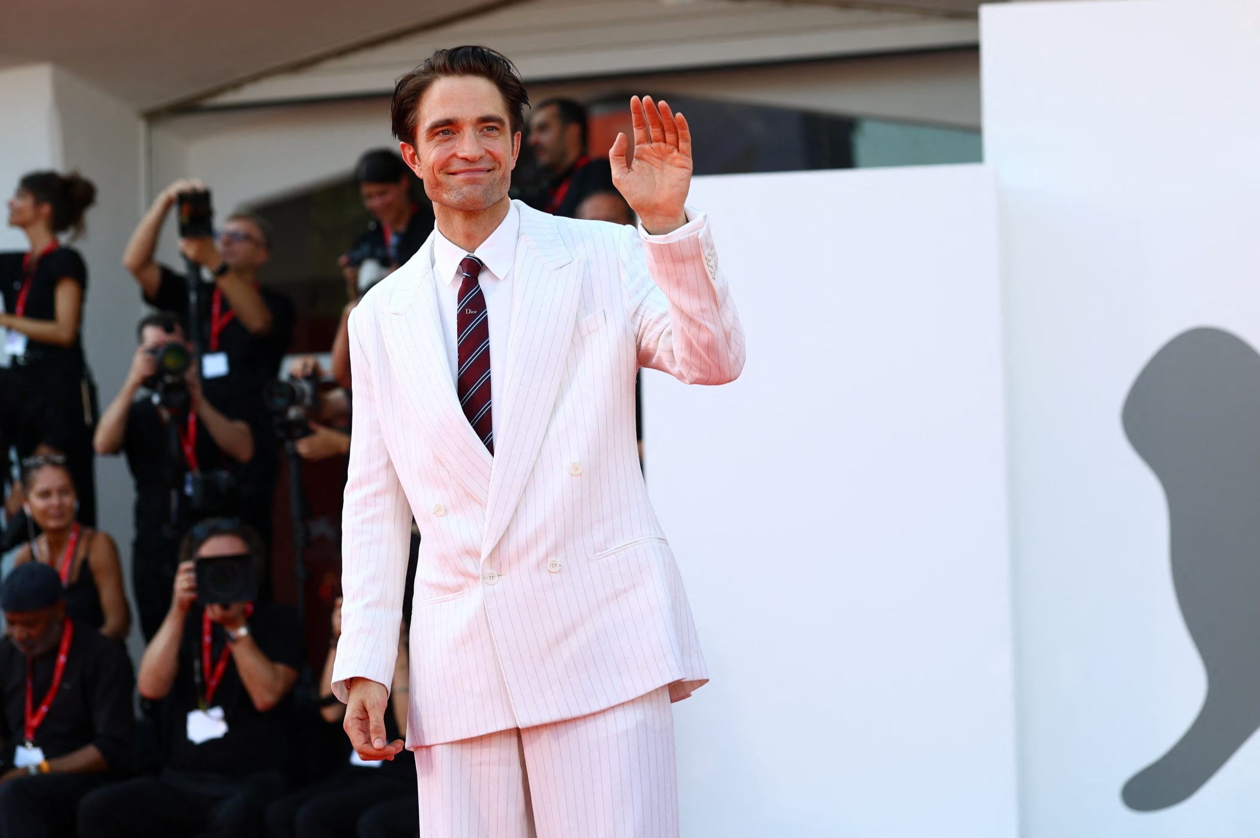 La chaqueta cruzada y el pantalón amplio reforzaron en Venecia una silueta retro dentro del look de Robert Pattinson. (REUTERS/Yves Herman)