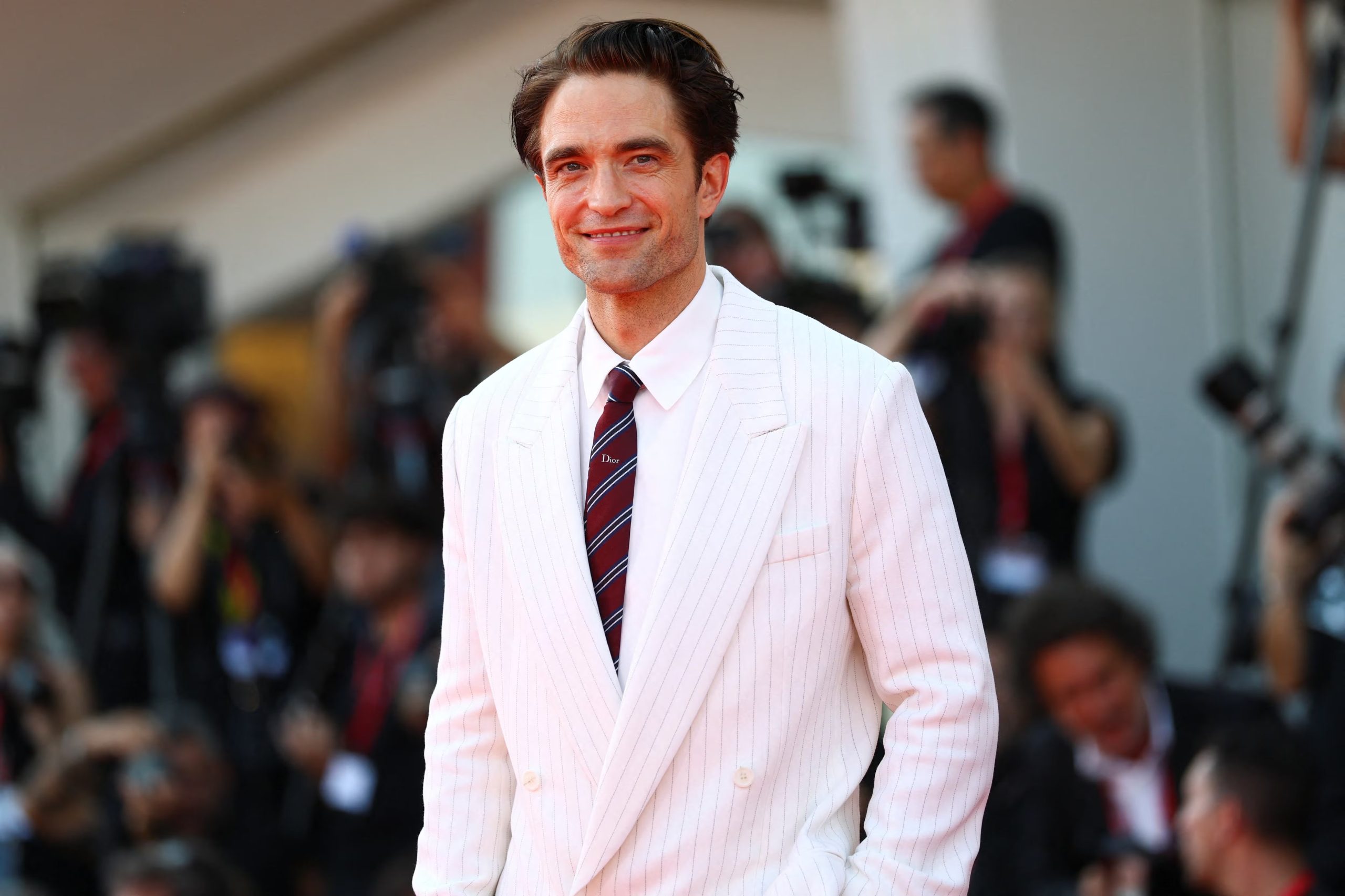 La corbata bordo con rayas diagonales aportó contraste sobre la camisa blanca y sostuvo la formalidad del estilismo de Robert Pattinson. (REUTERS/Yves Herman)