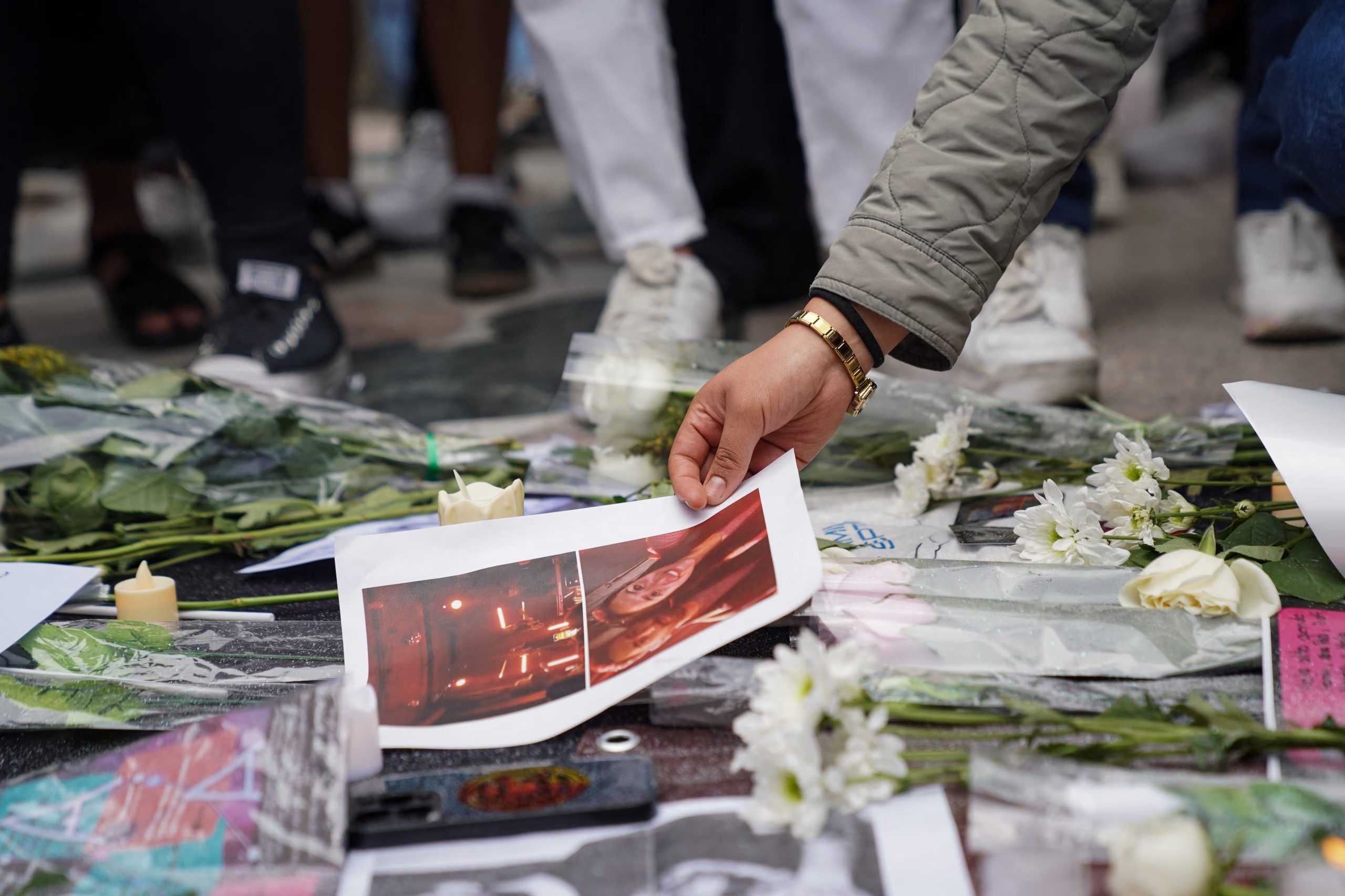 A person lays down a picture amid flowers, as fans of Mexican band Camilo Septimo gather at the Angel de la Independencia to honor keyboardist Jonathan 