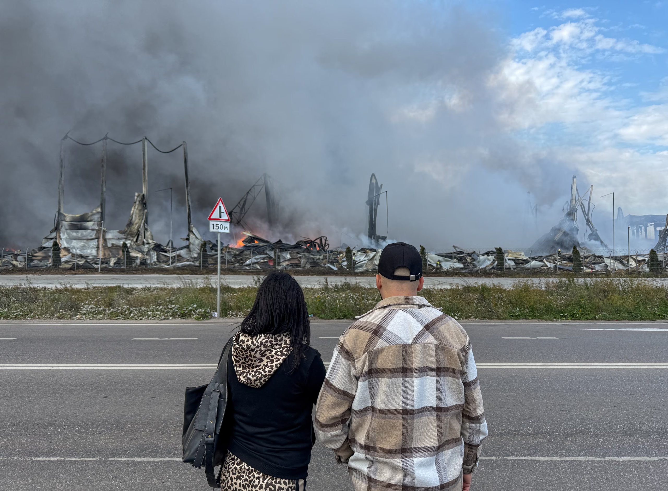 Dos personas observan el incendio en los almacenes de Wildberries, alcanzados por drones ucranianos en Koledino, región de Moscú, en agosto pasado. Los ataques a este tipo de centros logísticos ya provocaron pérdidas por más de 10.000 millones de dólares (REUTERS/Stringer)