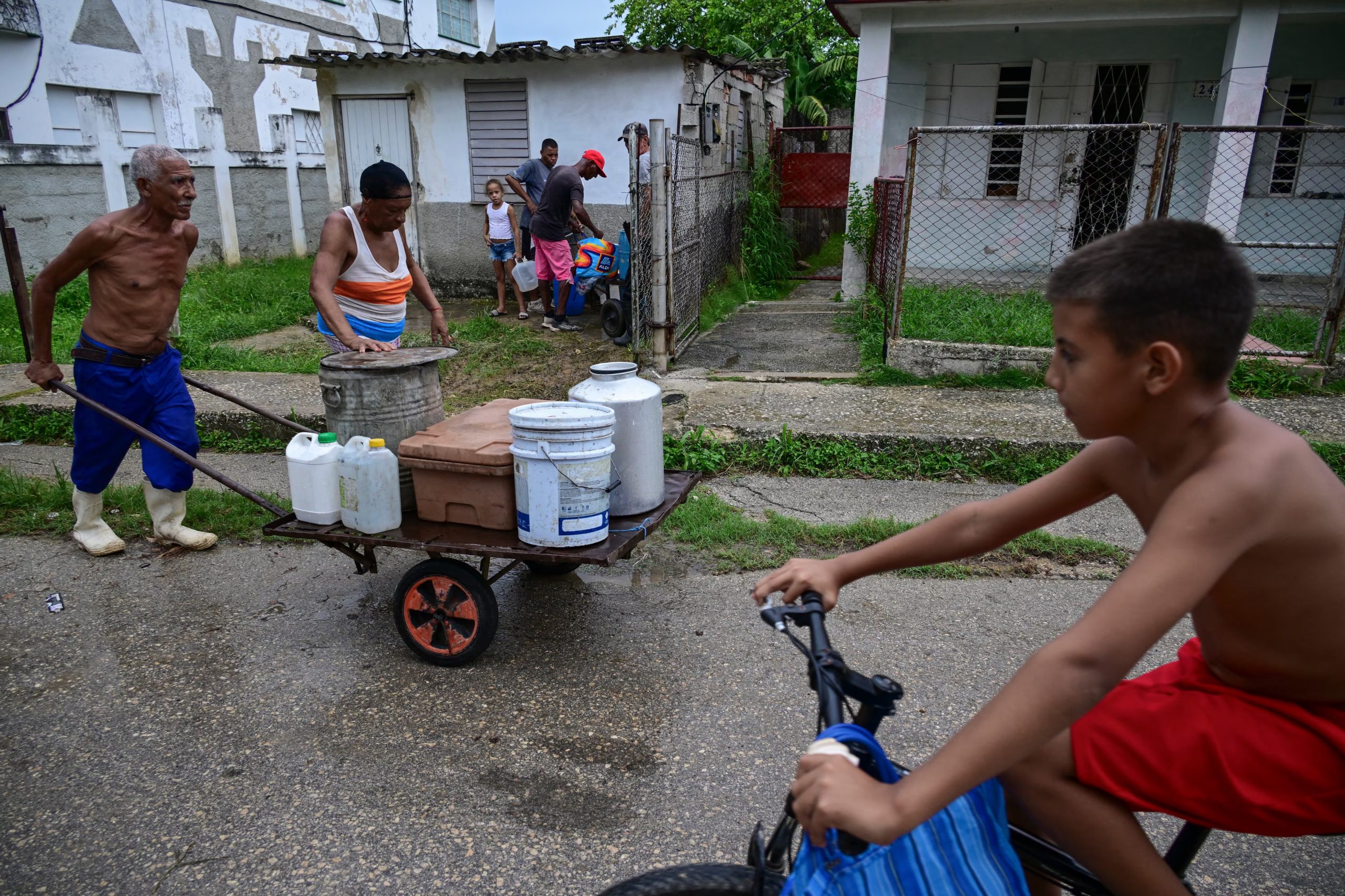 Adultos de la tercera edad se ven obligados a buscar y empujar carritos con cubetas o bidones con agua. (Infobae Cuba/ YAMIL LAGE / AFP)