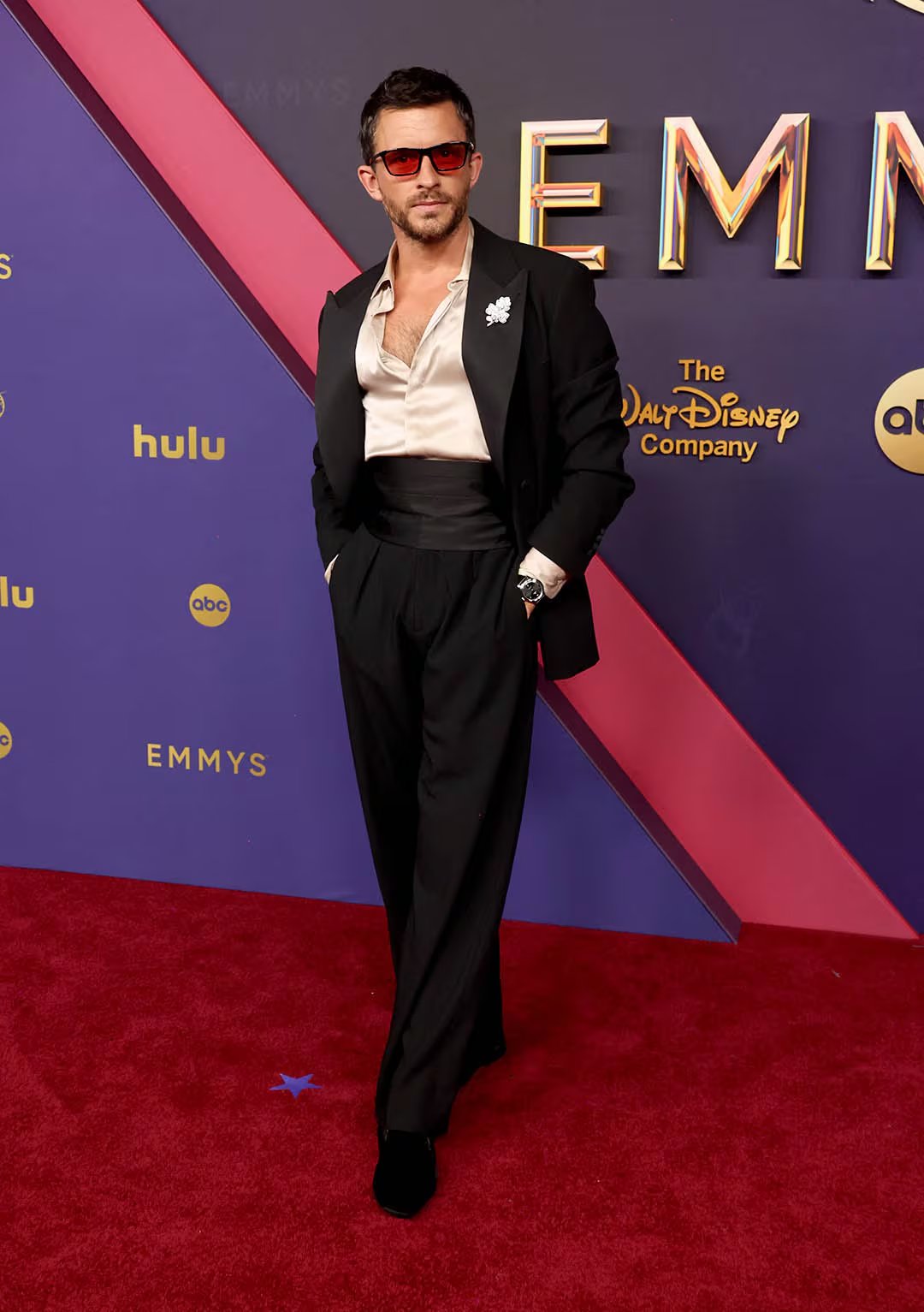 Jonathan Bailey incorpora una camisa satinada en gris perla a un traje negro de corte tradicional