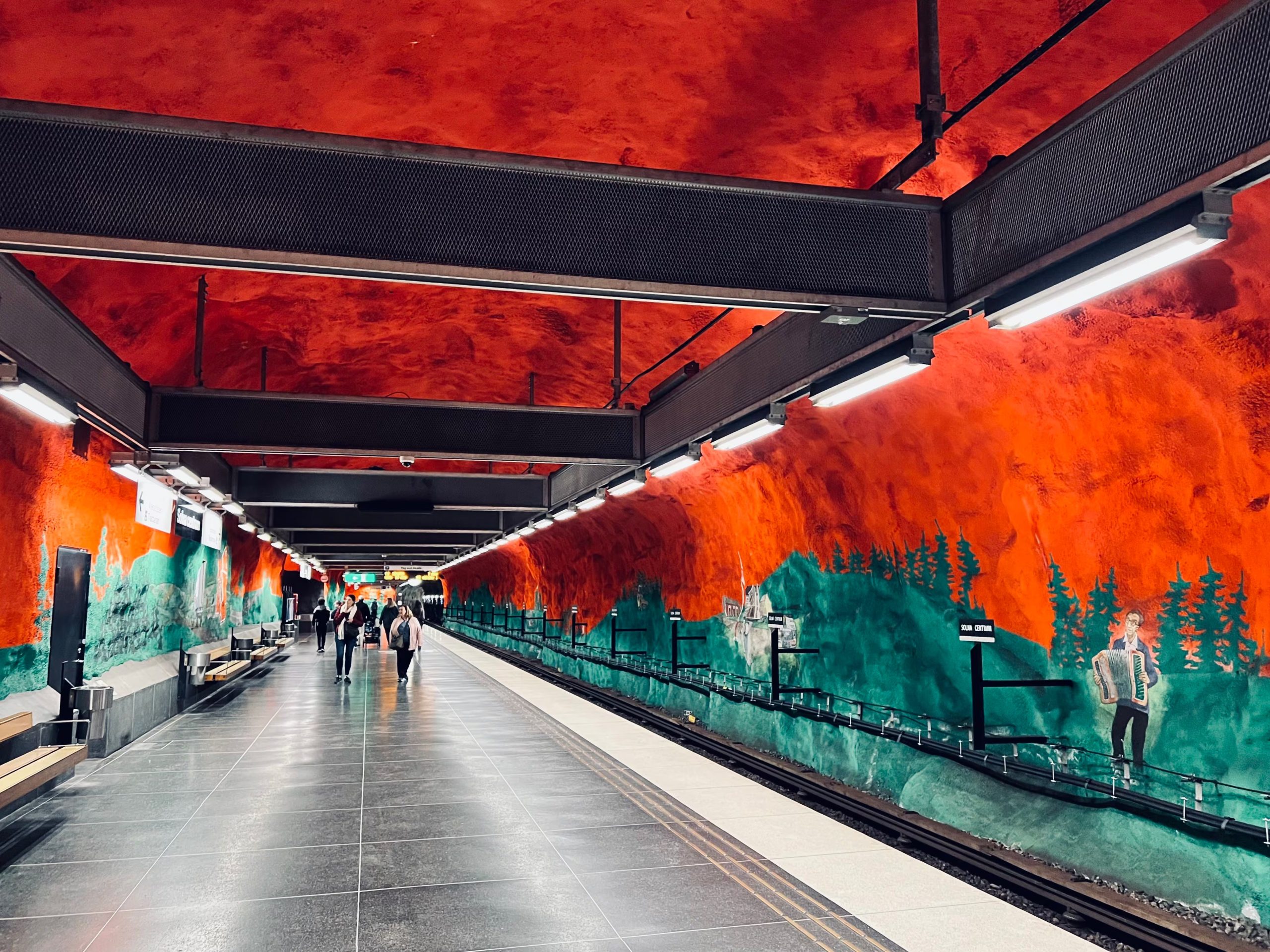 El techo rojo y los murales de pinos verdes de Solna Centrum transforman esta estación del metro de Estocolmo en una caverna de granito que alude a la deforestación y al éxodo rural en Suecia 