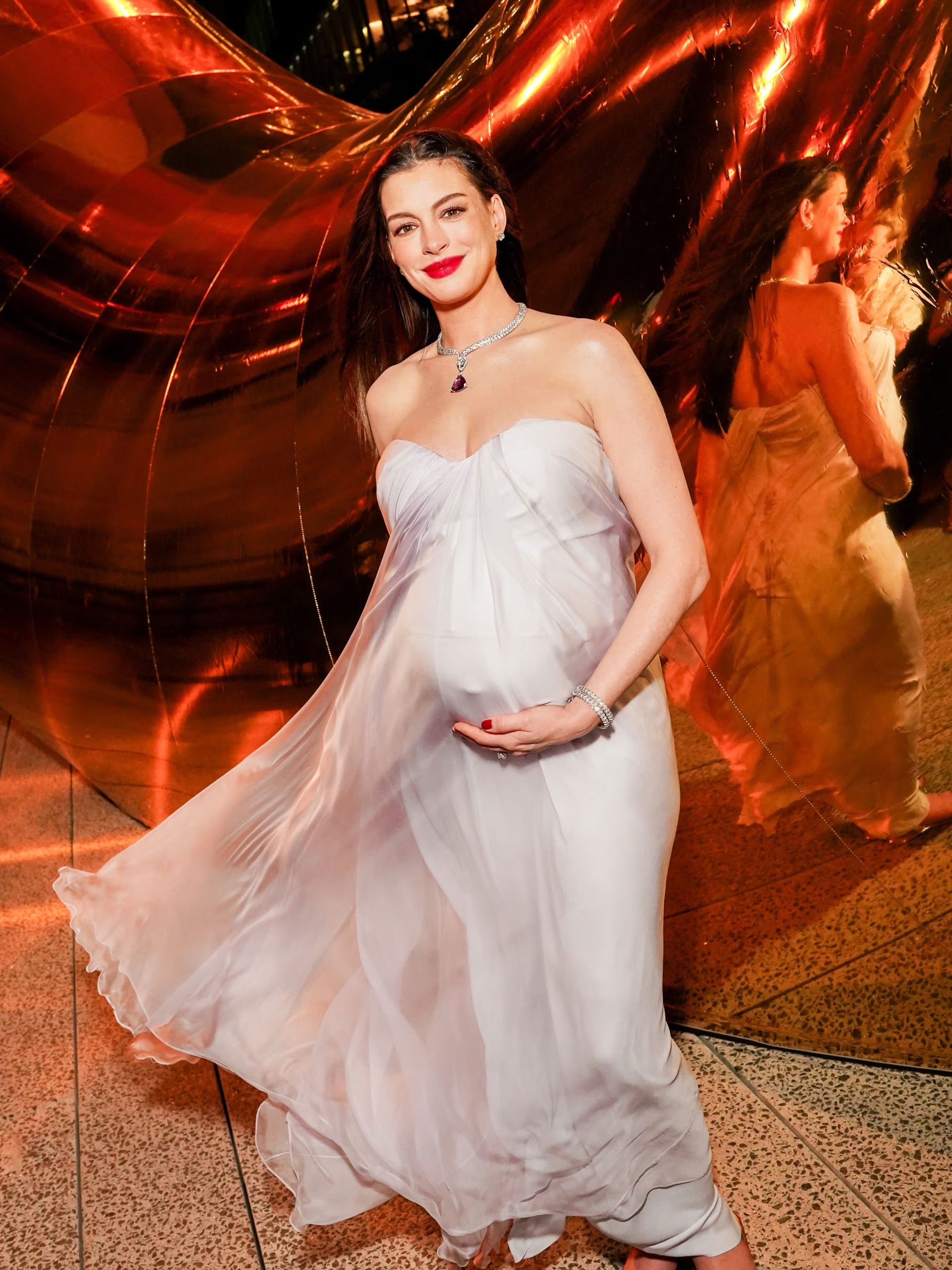 Anne Hathaway mostró su embarazo con una silueta fluida y una capa translúcida sobre la falda (Instagram Bvlgari)
