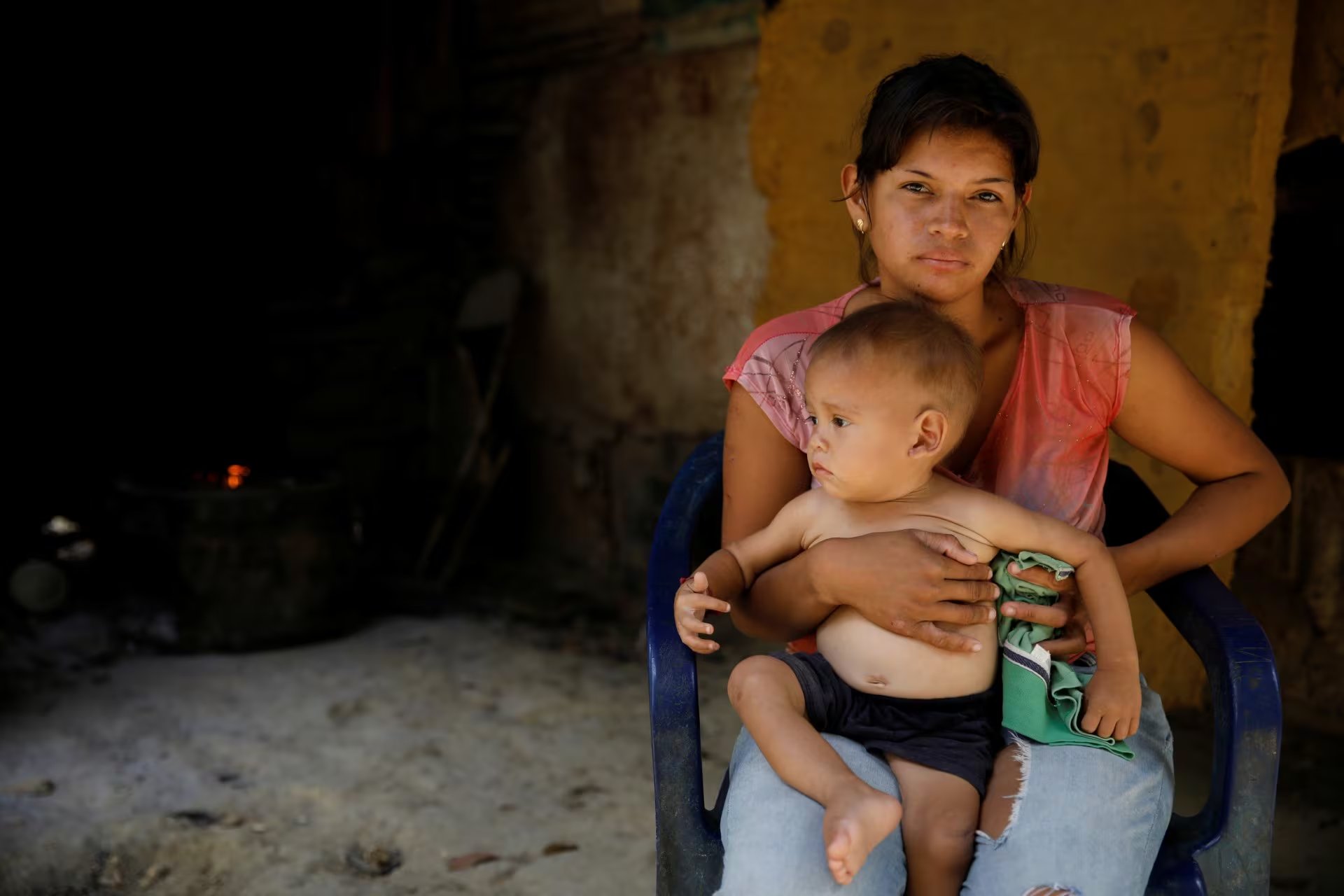 María Guitia posa una fotografía con su bebé de un año Yeibe Medina sobre su rodilla en su casa cerca de San Francisco de Yare, Venezuela, 18 de febrero de 2019. La pareja vive con los cinco hermanos y padres de Guitia en un cobertizo de una habitación. Con piso de tierra y sin agua corriente. El trabajo es escaso y viven de los pagos por trabajos ocasionales y de una entrega mensual del gobierno de suministros alimentarios básicos fuertemente subsidiados. Se han dedicado a inventar comidas con lo poco que tienen, como las lentejas con plátano de los árboles en su patio trasero. Guitia dijo que su hijo había perdido peso durante los últimos cinco meses hasta que Caritas les dio algunos suplementos nutricionales. REUTERS / Carlos Garcia Rawlins BUSQUE
