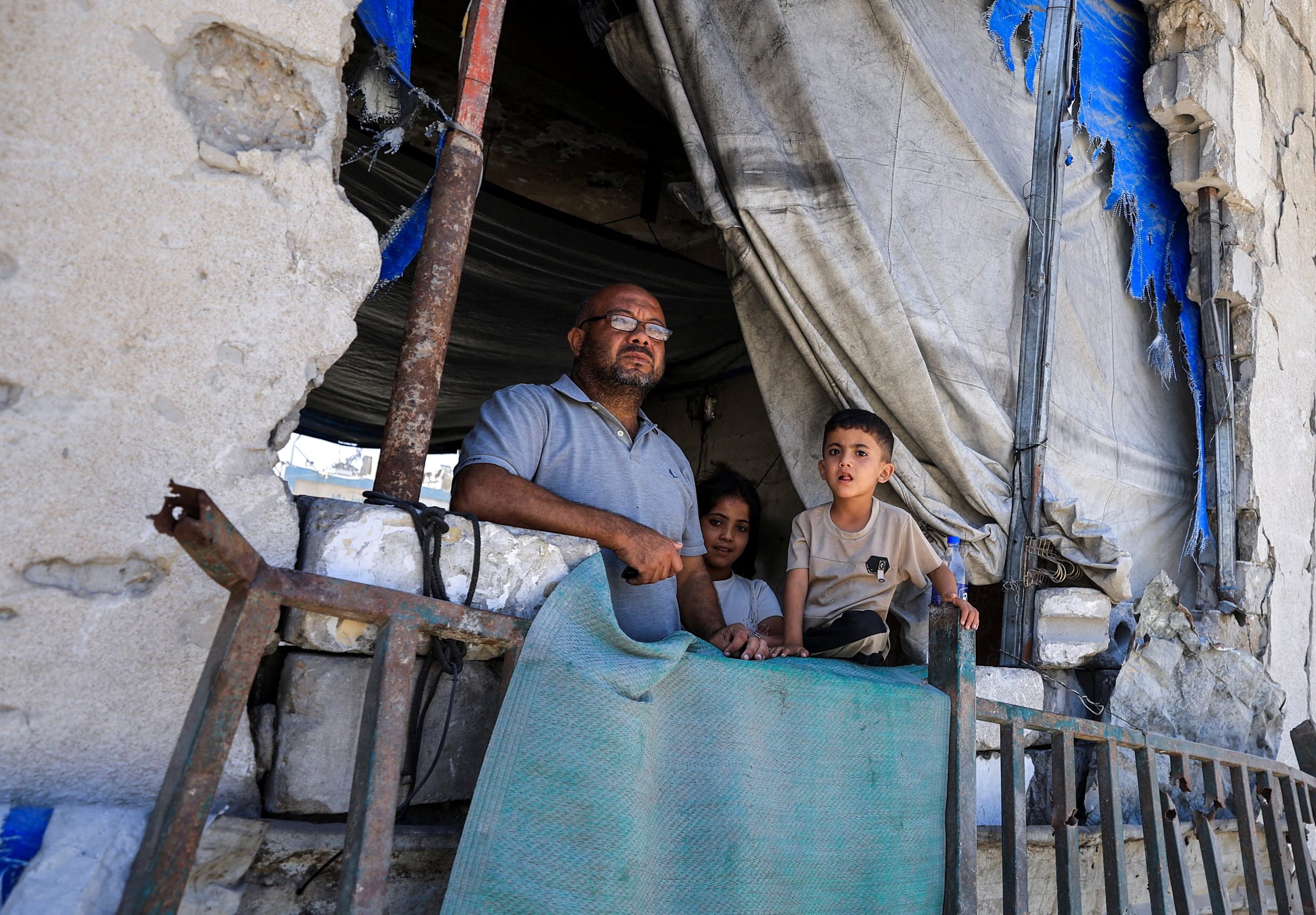 Un palestino y dos niños observan las tareas de trabajadores de Defensa Civil, que intentan rescatar a personas atrapadas bajo los escombros de un edificio residencial, dañado en un ataque israelí durante la guerra y que colapsó este miércoles, en Ciudad de Gaza, el 16 de septiembre de 2026 (REUTERS/Dawoud Abu Alkas)