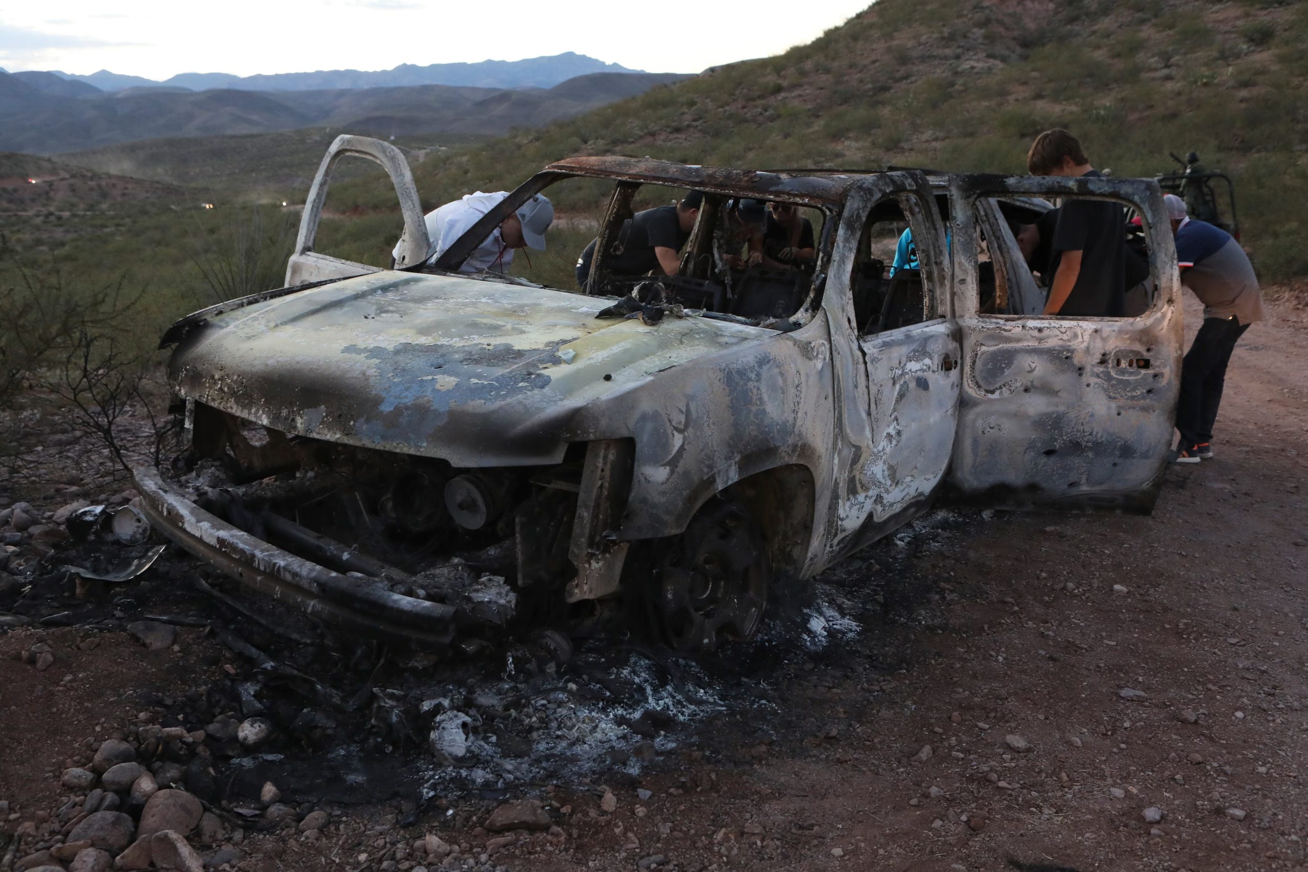 Miembros de la familia LeBarón observan el vehículo calcinado donde perdieron la vida y fueron quemados algunos de los nueve integrantes de la familia asesinados durante una emboscada perpetrada por hombres armados en la sierra de Bavispe, Sonora (México), el 5 de noviembre de 2019. — El presidente de Estados Unidos, Donald Trump, ofreció el martes ayudar a México a 