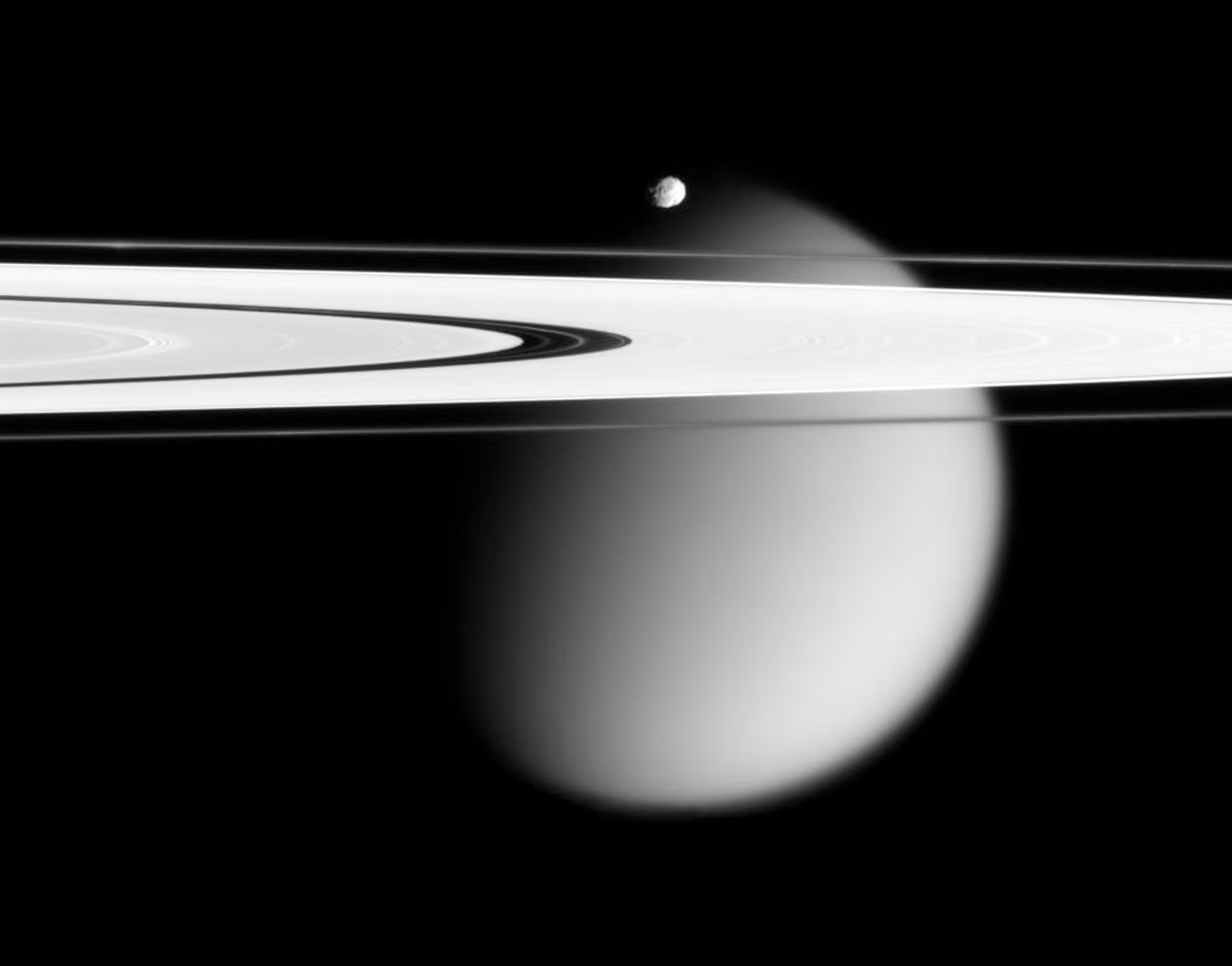 Dos de las lunas de Saturno, la pequeña Epimeteo y Titán, envuelta en neblina, con los anillos A y F de Saturno extendiéndose por el marco (NASA vía AP)