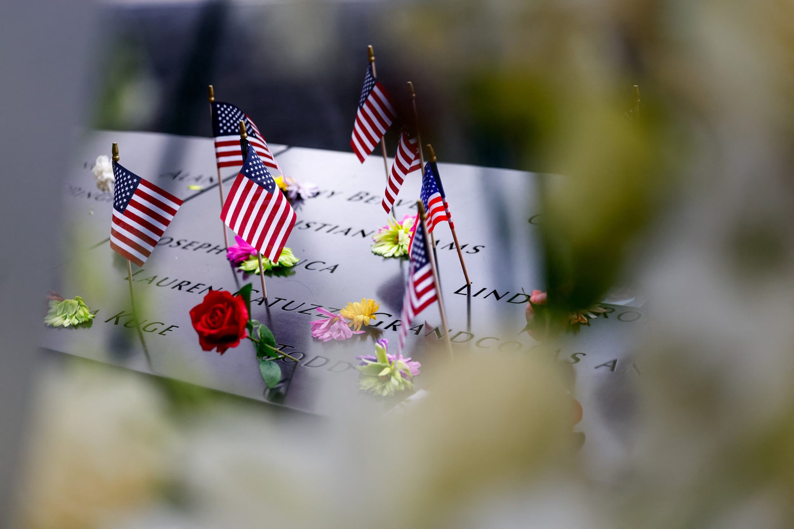 Flores y banderas de Estados Unidos junto a las piscinas reflectantes del Memorial del 11-S (REUTERS/Jeenah Moon/Pool)