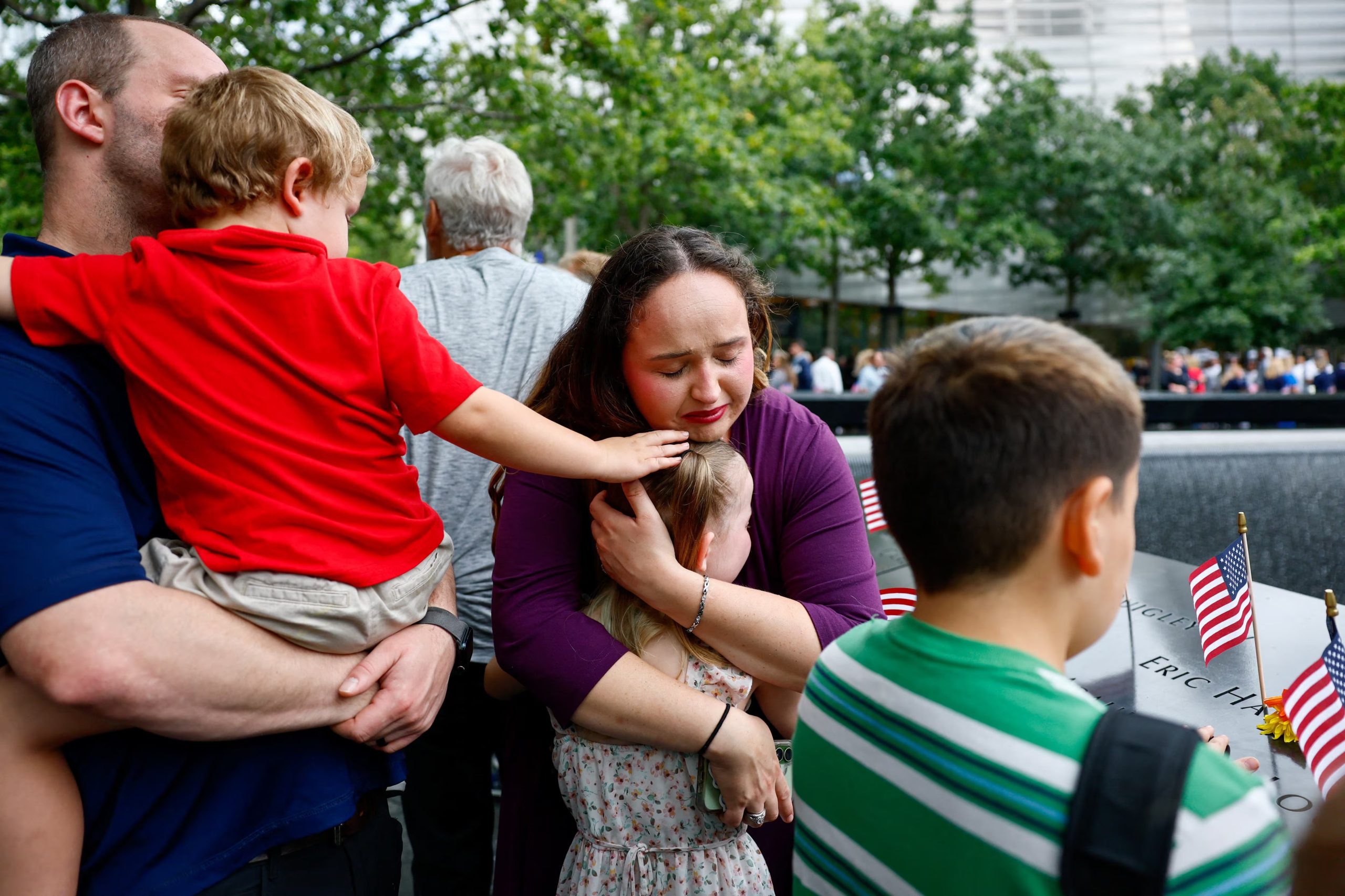 Heidi Peters abraza a su hija Hazel Reeves, de 7 años, mientras rinden homenaje al abuelo de Heidi, Louis Neil Mariani, junto a los estanques reflectantes del Memorial del 11-S (REUTERS/Jeenah Moon/Pool)