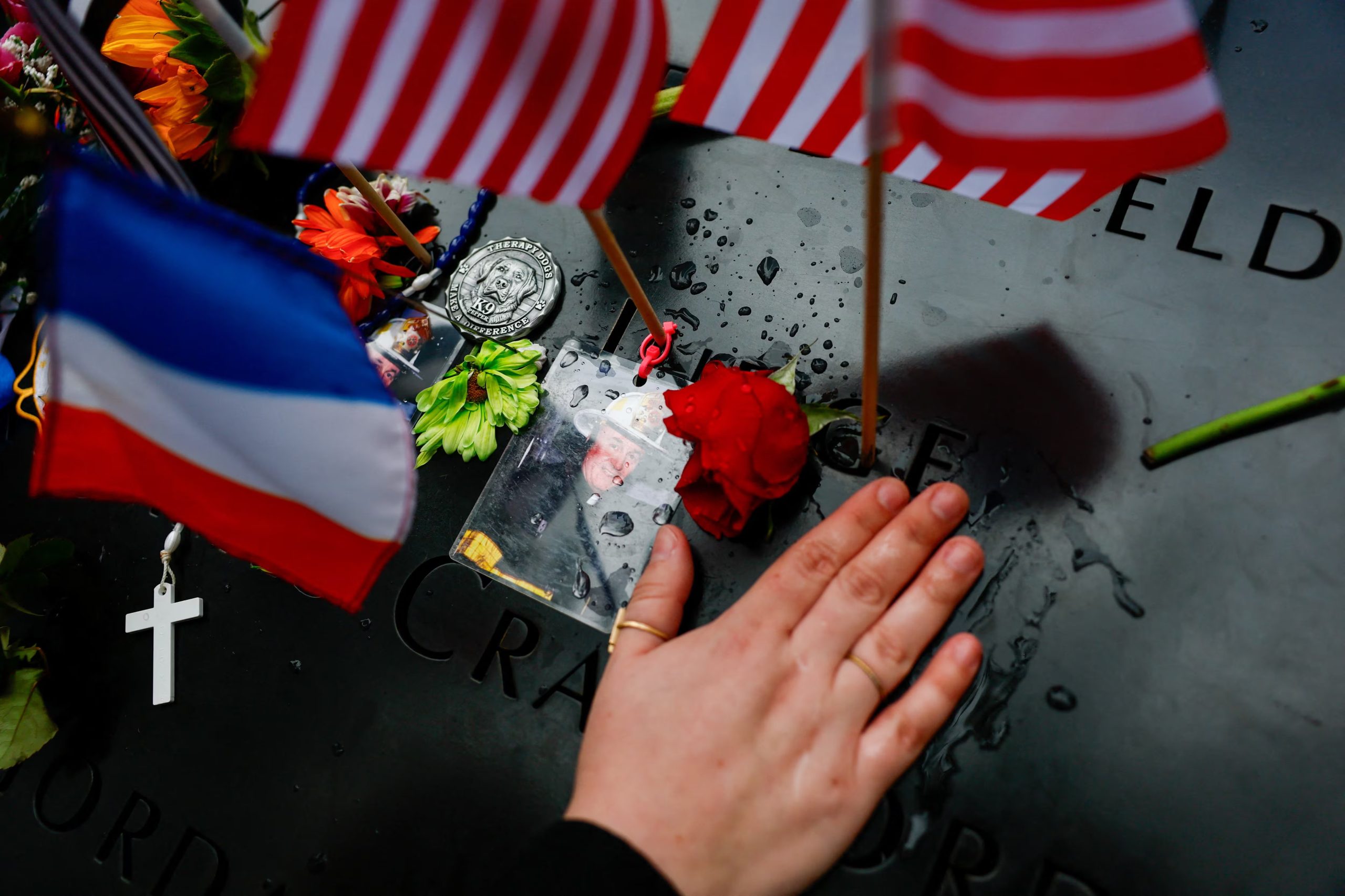 Una persona coloca su mano sobre una fotografía del padre Mychal Judge, junto a los estanques reflectantes del Memorial del 11-S (REUTERS/Jeenah Moon/Pool)