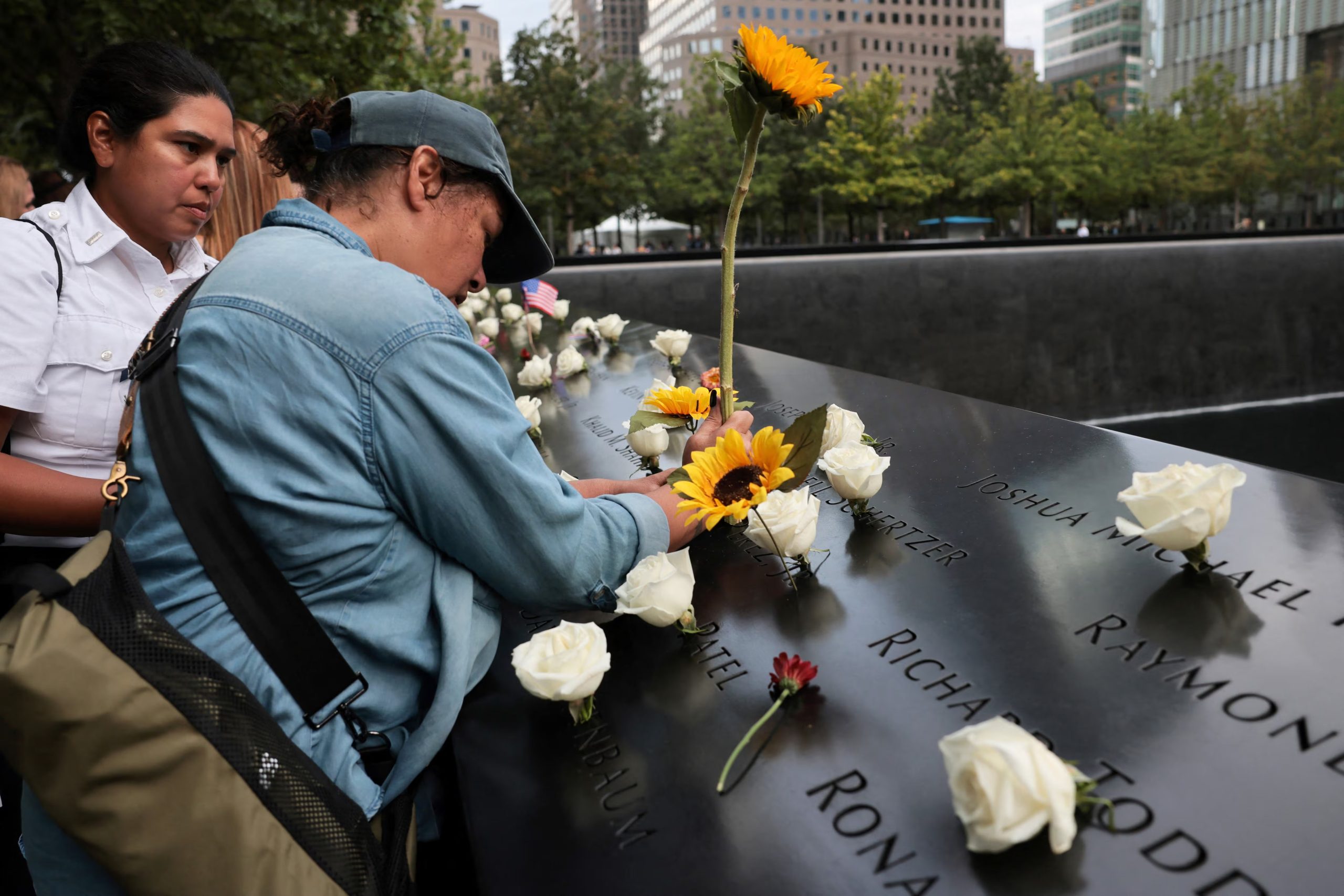 Personas dejan recuerdos en el monumento antes de una ceremonia que conmemora el 25 aniversario de los ataques del 11 de septiembre de 2001 (Spencer Platt/Pool vía REUTERS)
