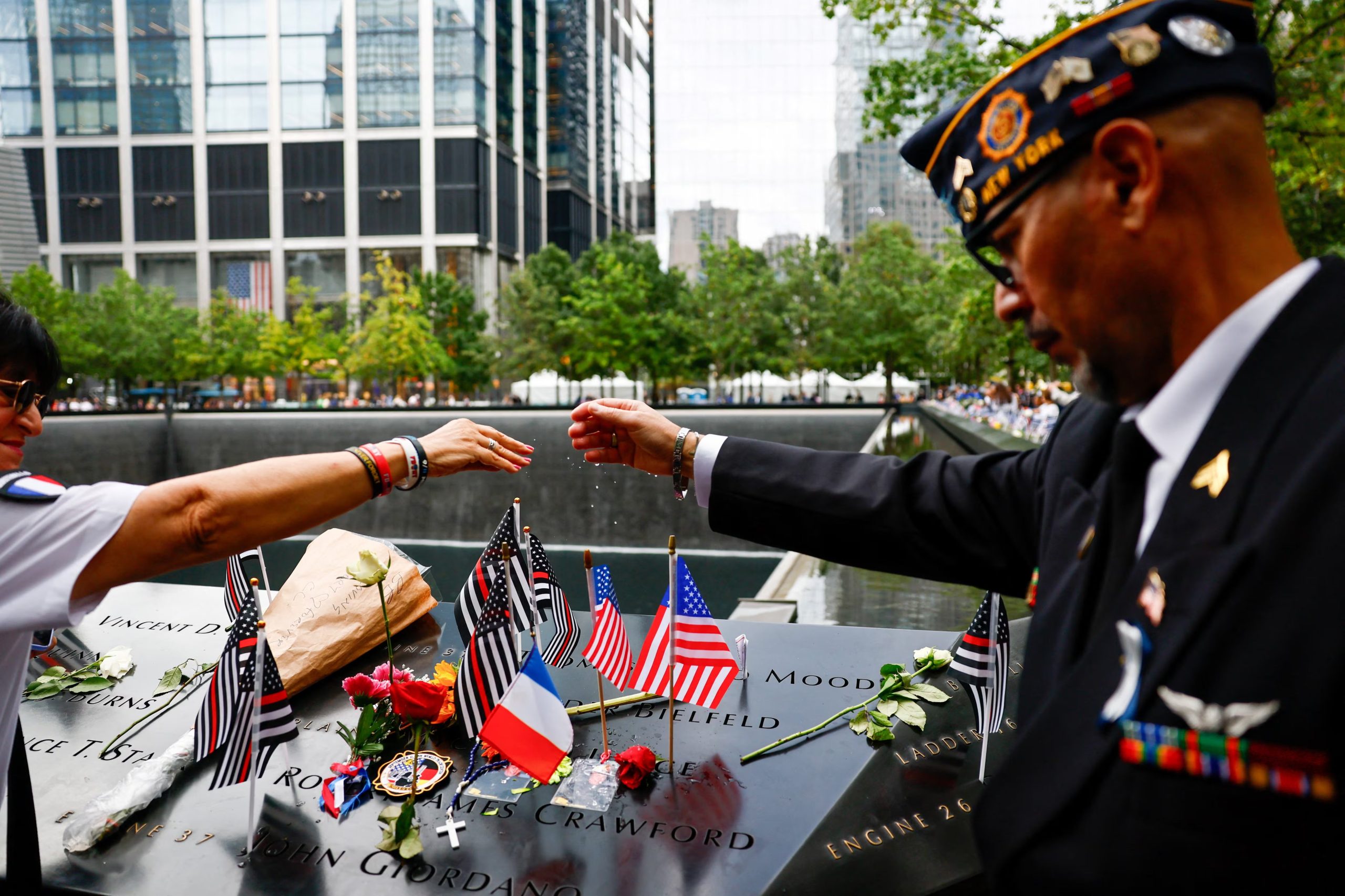 Varias personas juntan las manos en oración por el padre Mychal Judge, junto a los estanques reflectantes del Memorial del 11-S (REUTERS/Jeenah Moon/Pool)