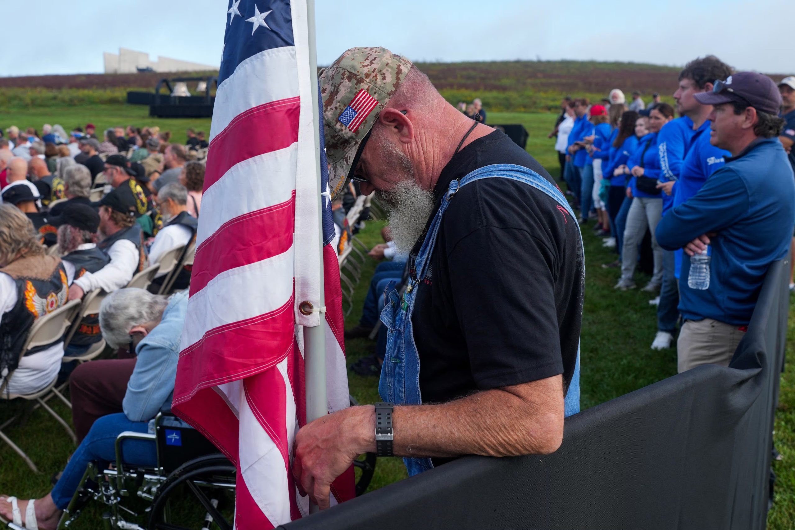 Un hombre mira hacia abajo mientras permanece de pie junto a una bandera estadounidense durante una ceremonia celebrada en el Monumento Nacional del Vuelo 93, en conmemoración de las víctimas del accidente aéreo ocurrido el 11 de septiembre de 2001, cuando el avión secuestrado se estrelló en un campo abierto. La ceremonia tuvo lugar en el 25.º aniversario de los atentados del 11 de septiembre de 2026 en Stonycreek Township, cerca de Shanksville, en el condado de Somerset, Pensilvania, EE. UU. REUTERS/Nathan Howard