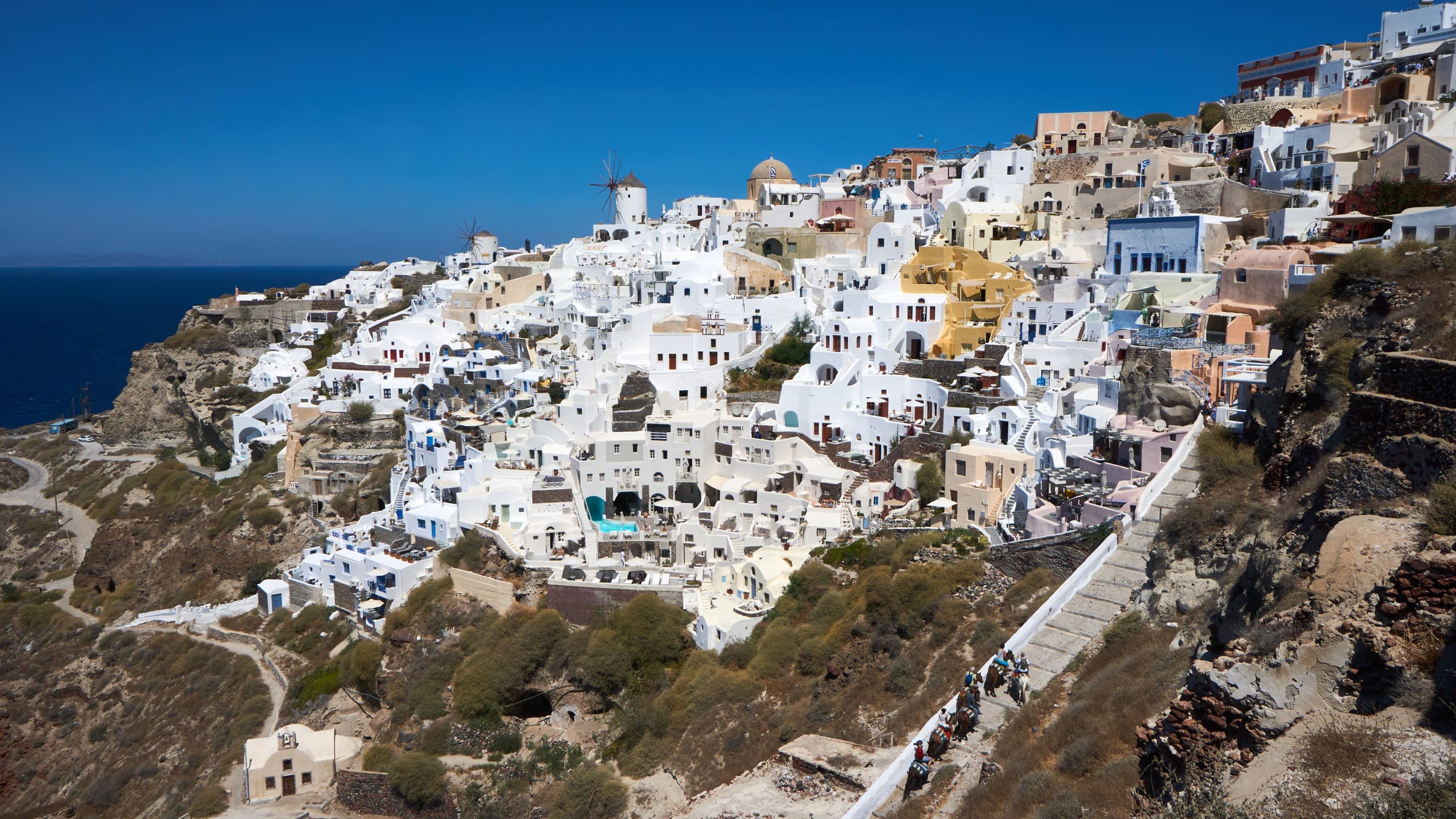 Las casas encaladas con cúpulas azules de Santorini surgen sobre el borde de una caldera sumergida en el mar Egeo (Wikipedia)