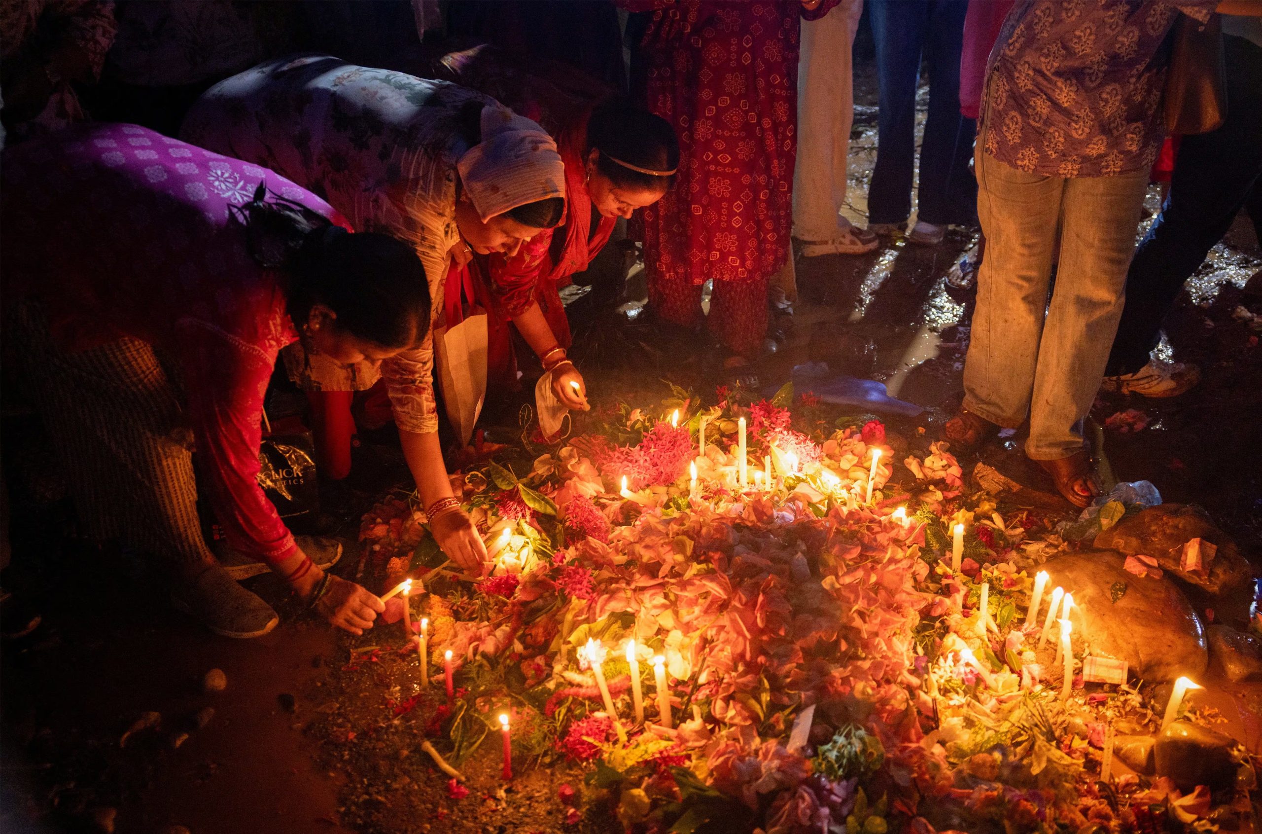Personas colocan velas y flores en el lugar de entierro colectivo de Devghat para las víctimas de las mortales inundaciones repentinas y deslizamientos de tierra, mientras llueve en Chitwan, Nepal, el 1 de septiembre de 2026 (REUTERS/Adnan Abidi)